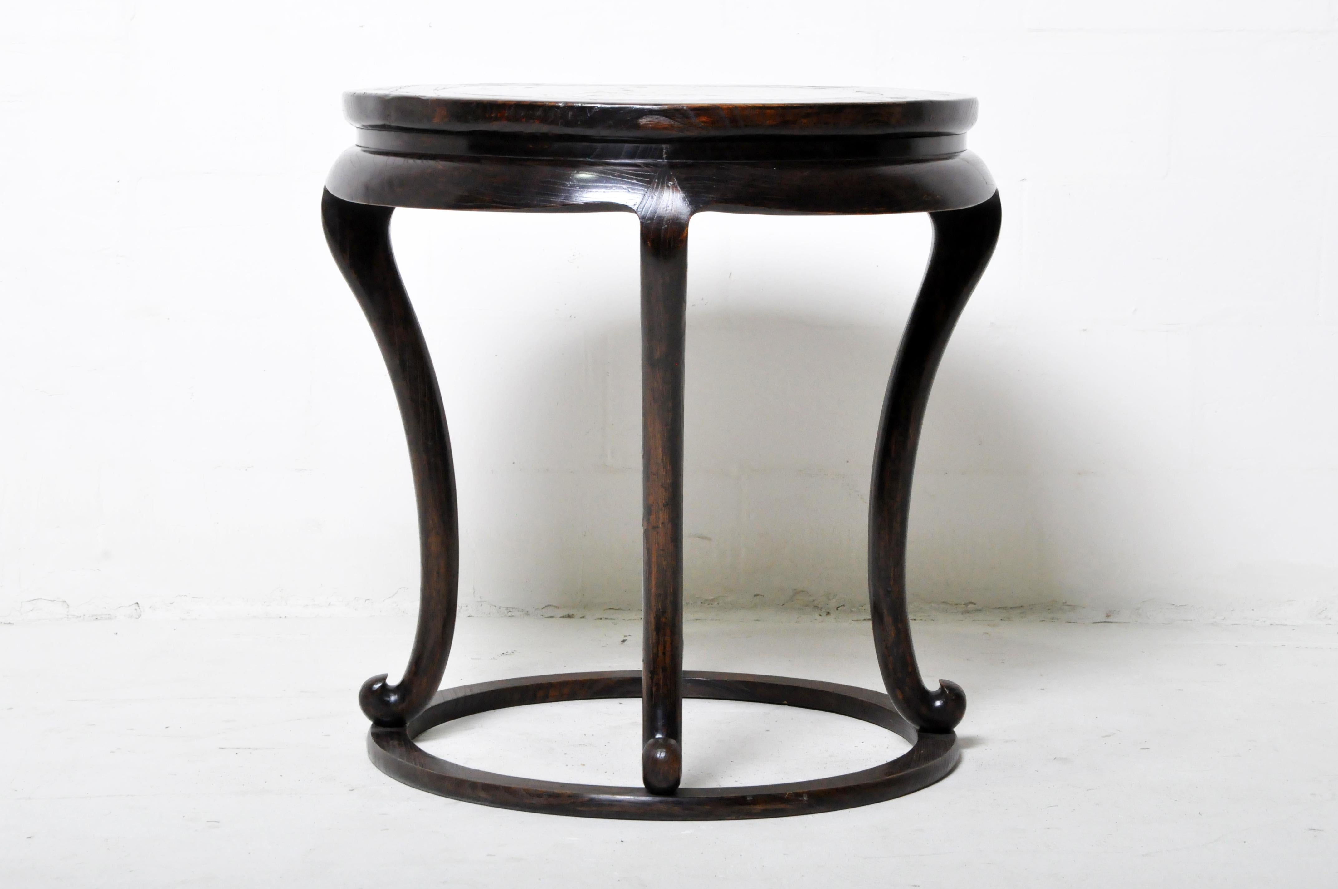 This elegant cabriole-legged table once held an incense burner in an elegant home or ancestral shrine. It is made from elmwood and protected by dark oxblood lacquer. The stone insert is green marble. It is of Northern Chinese origin and dates to the