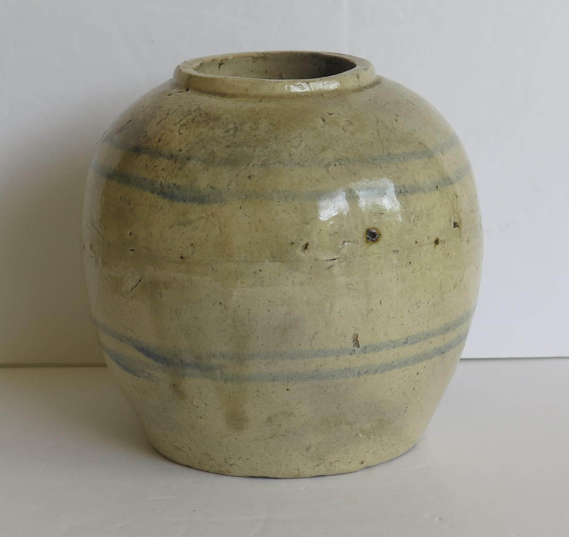 This is a Chinese handcrafted ceramic provincial jar or vase with a light celadon glaze which we date to the Ming period of the early 17th century or possibly earlier.

The jar is handcrafted, strongly potted with a short neck and simply decorated