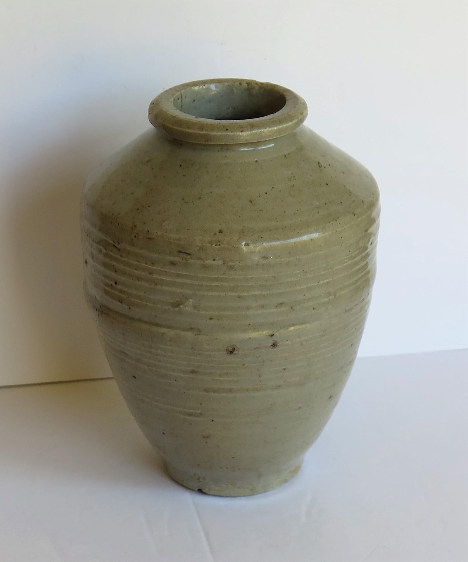 This is a Chinese handcrafted ceramic Yao jar or vase with a Celadon Glaze which we date to the Ming period of the early 17th century or possibly earlier.

The jar is handcrafted, strongly potted with a cylindrical tapering form, high shoulder,