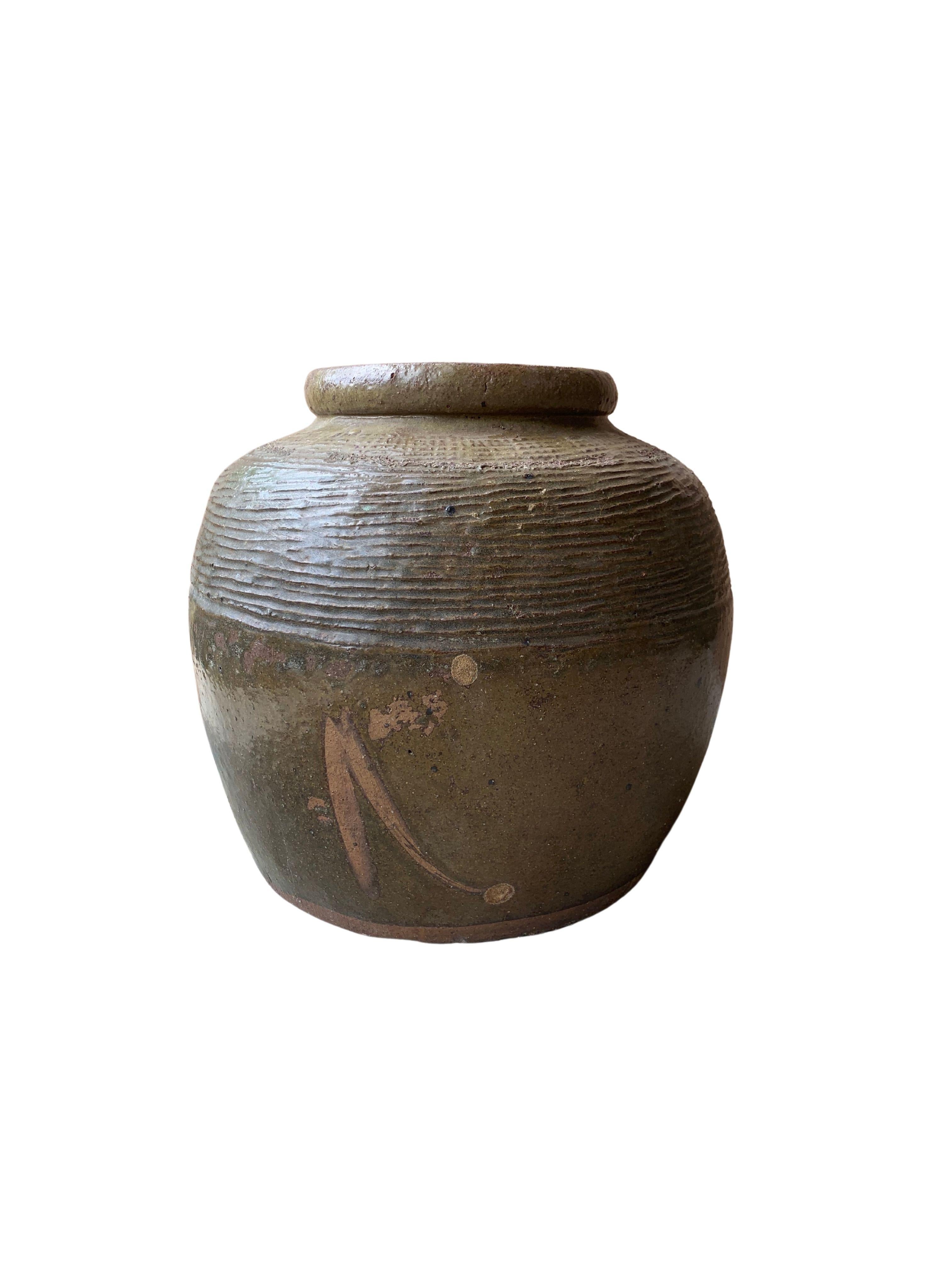 This glazed Chinese ceramic jar was once used for pickling foods. It features a jade green finish and outer surface that features a ribbed texture. A great example of Chinese pottery, with its imperfections and ageing over the years contributing to