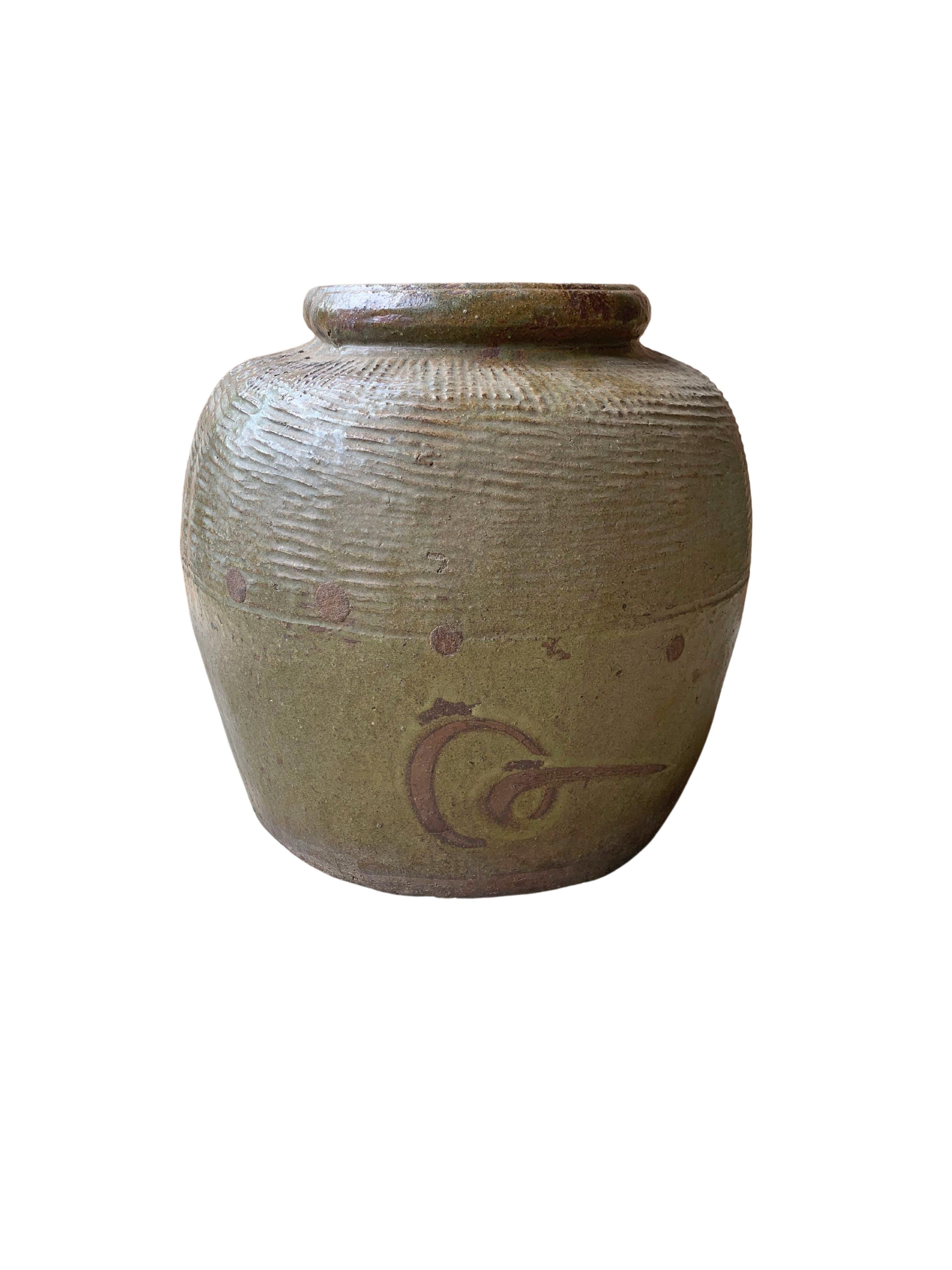 This glazed Chinese ceramic jar was once used for pickling foods. It features a jade green finish and outer surface that features a ribbed texture. A great example of Chinese pottery, with its imperfections and ageing over the years contributing to