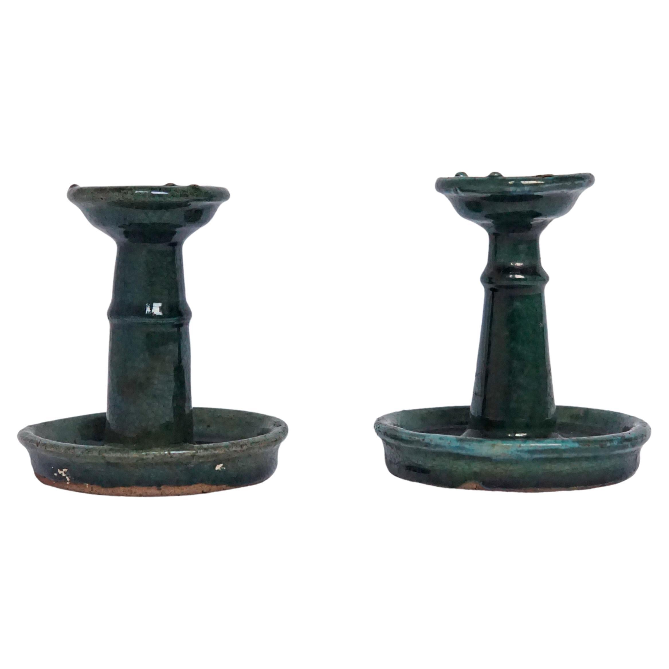 This set of Shiwan ware oil lamps from the early 20th century features the distinctive green glaze. Shiwan ware is a style of Chinese pottery from the Shiwanzhen district near Guangdong, China. This pair is small in size. 

Measures: diameter 11cm