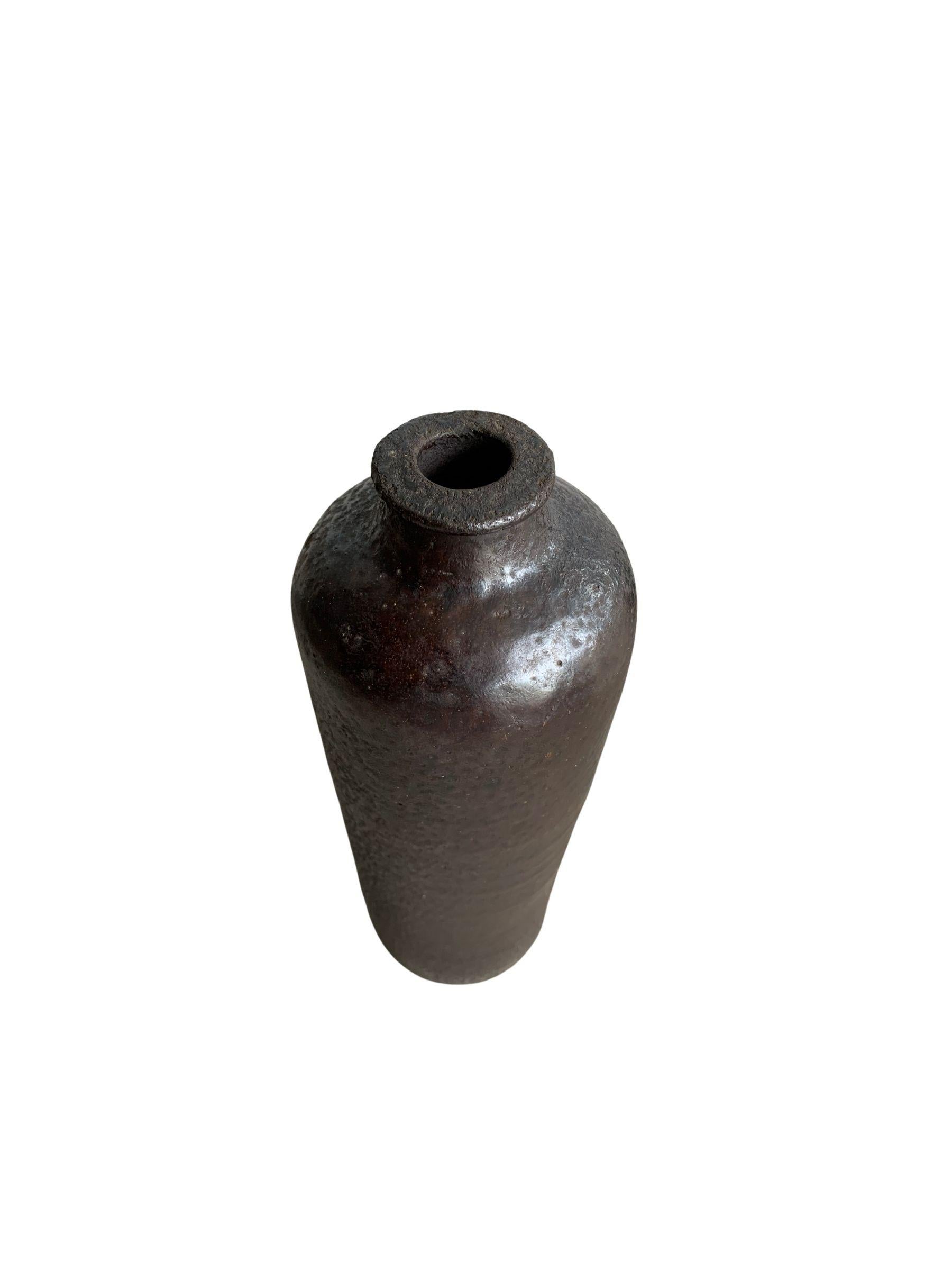 A visibly old ceramic wine bottle from 18th century China in a dark brown glaze. This bottle comes from Shanxi Provence and is a wonderful example of Chinese ceramics. This bottle features an age-related texture of indents and markings that add to