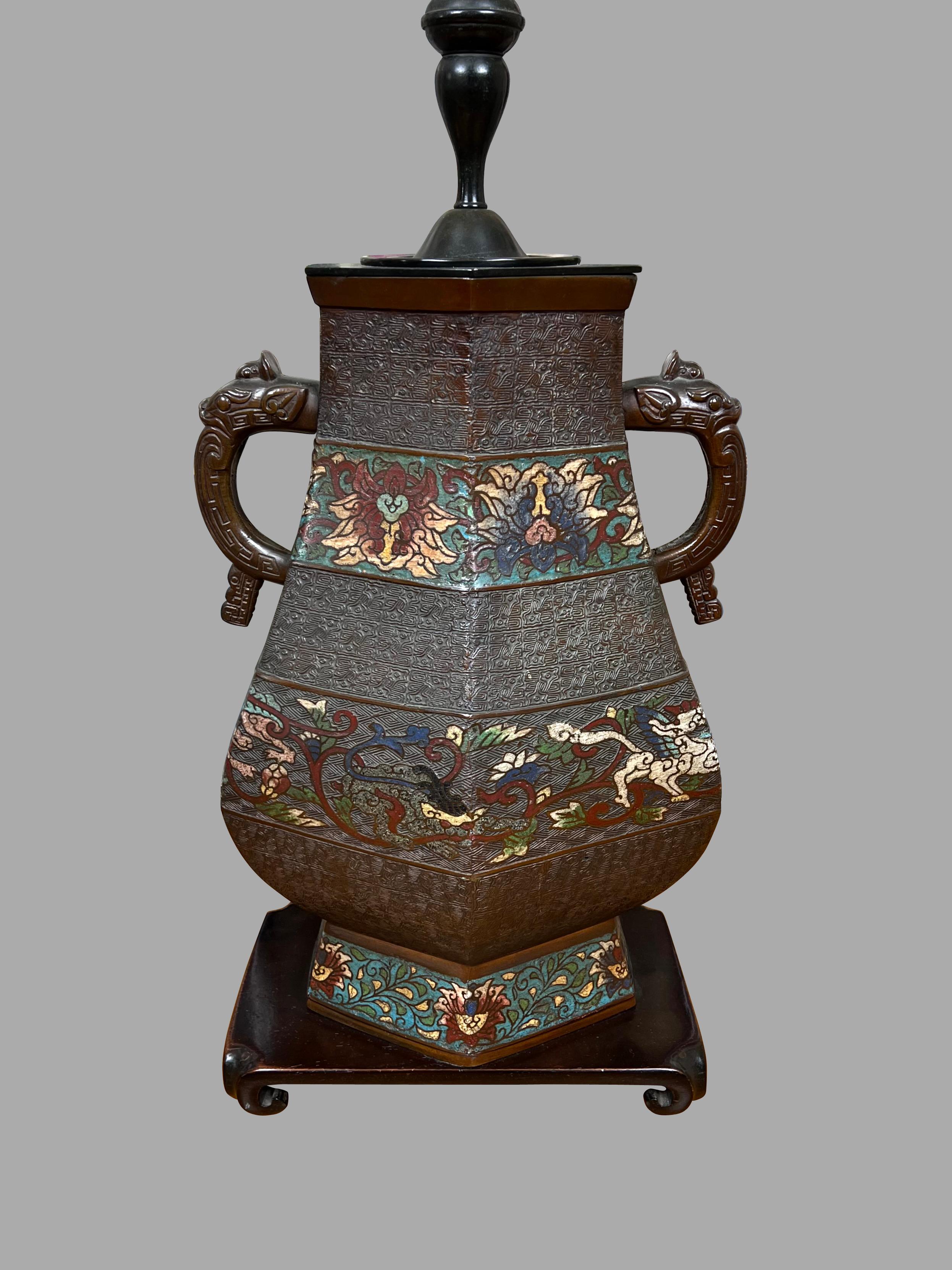 An attractive Chinese champleve table lamp of good scale, the 6 sided angular body made of bronze with enamel inlay in foliate designs.
The vase rests on a wooden plinth. Circa 1930-1960. Shade not included.