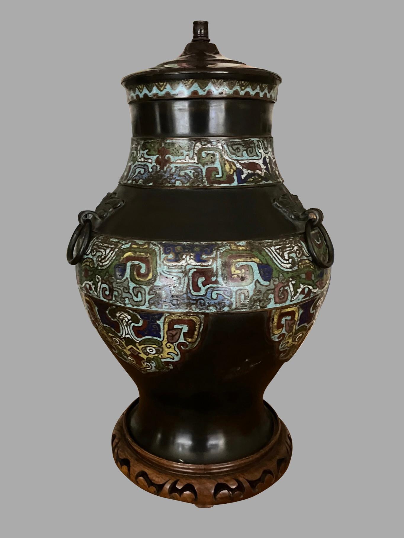 An attractive Chinese champleve lamp of substantial size decorated in blue, brown, and various other colored enamel, now mounted on a carved wooden base. Height to top of fittings is 27