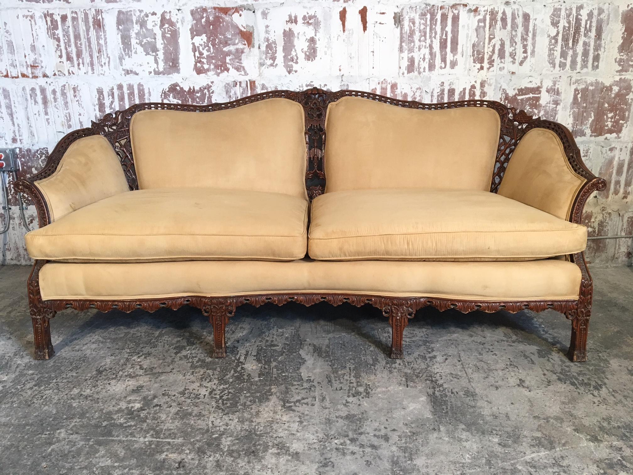 Hand carved sofa in Chinese chinoiserie style features intricate carvings and solid tan upholstery. Upholstered in a microfiber fabric. Good vintage condition with only minor signs of age appropriate wear. Professional reupholstery available.