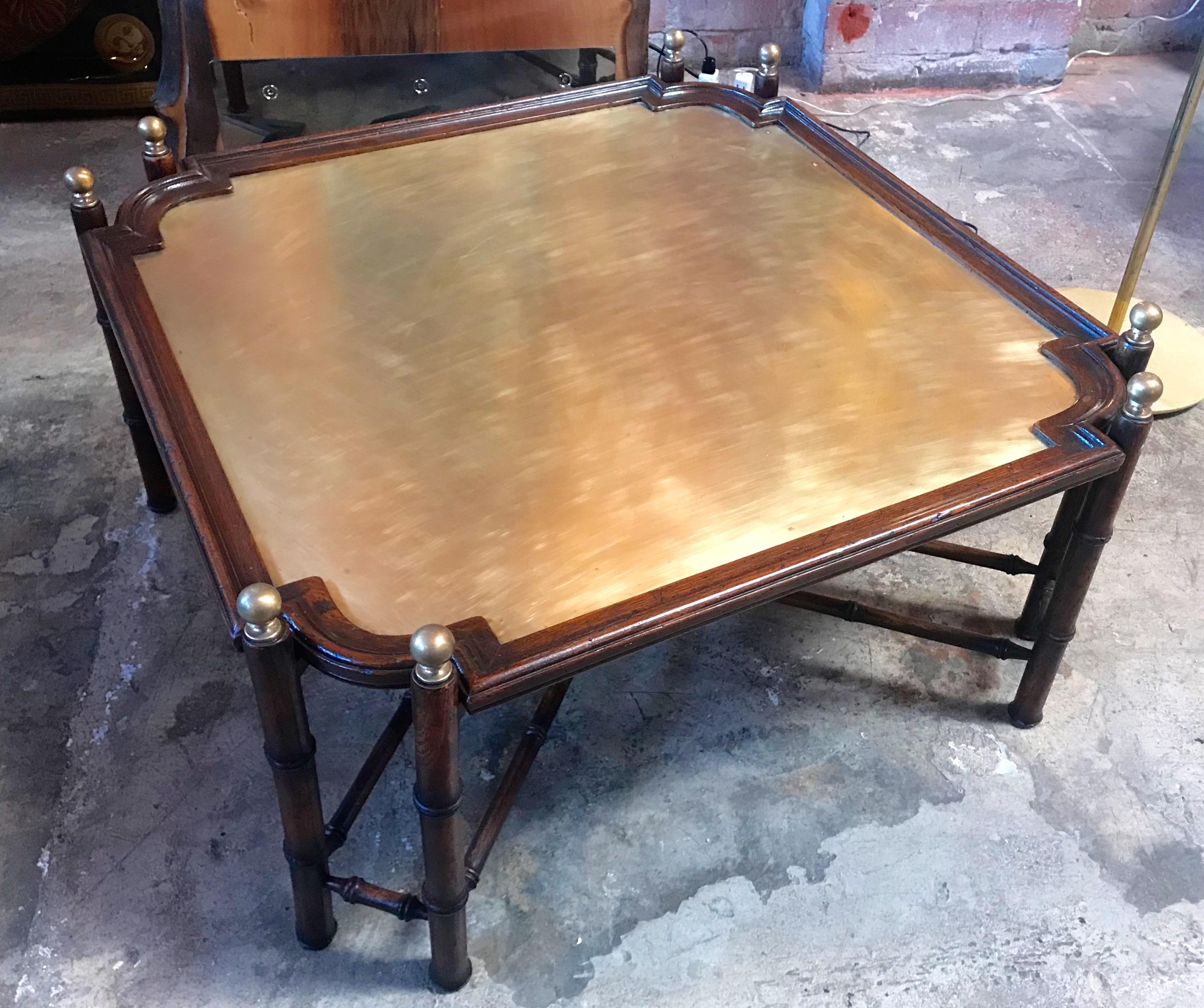 Large vintage coffee table of faux bamboo form wood base and removable tray top having a distinctive patinated brass top. This cocktail table has classic lines and solid brass finials mount on the top corners.