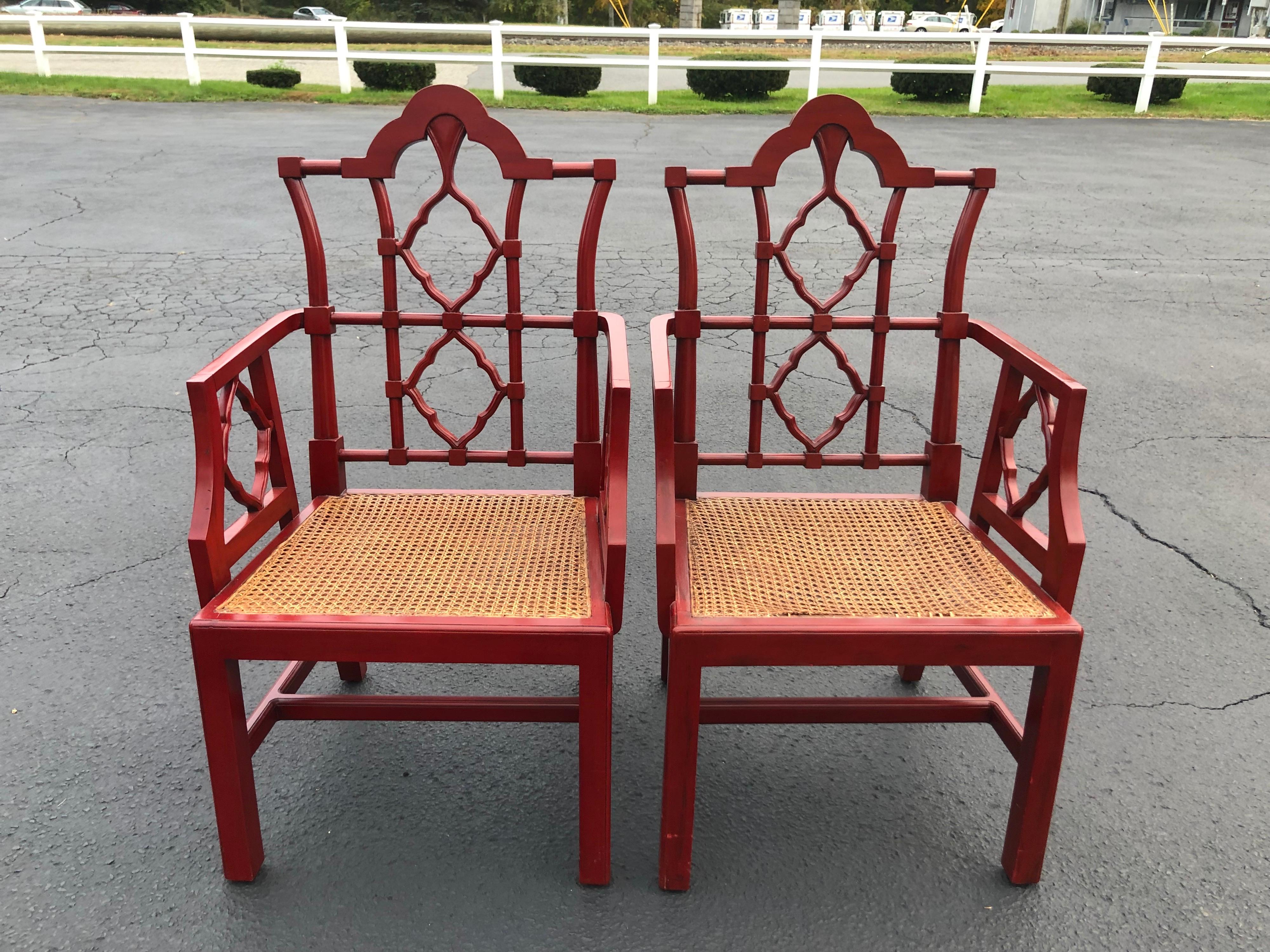 Chinese Chippendale Faux bamboo chairs in red. Nice large chair. Comfortable for a larger person. Perfect for the head ends of a table. Deep Pagoda red tone. Caned seats with custom cushions. One seats caning is lifting on one end . Asian throw