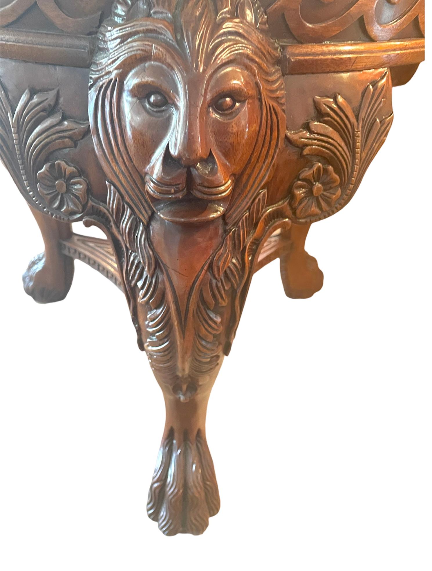 Chinese Chippendale style mahogany lions head claw feet pedestal dining table. Item features solid carved wood pedestal base with lions heads, claw feet, Greek key details, stretcher base, and bevelled glass round top is 43 inches- it was used as a