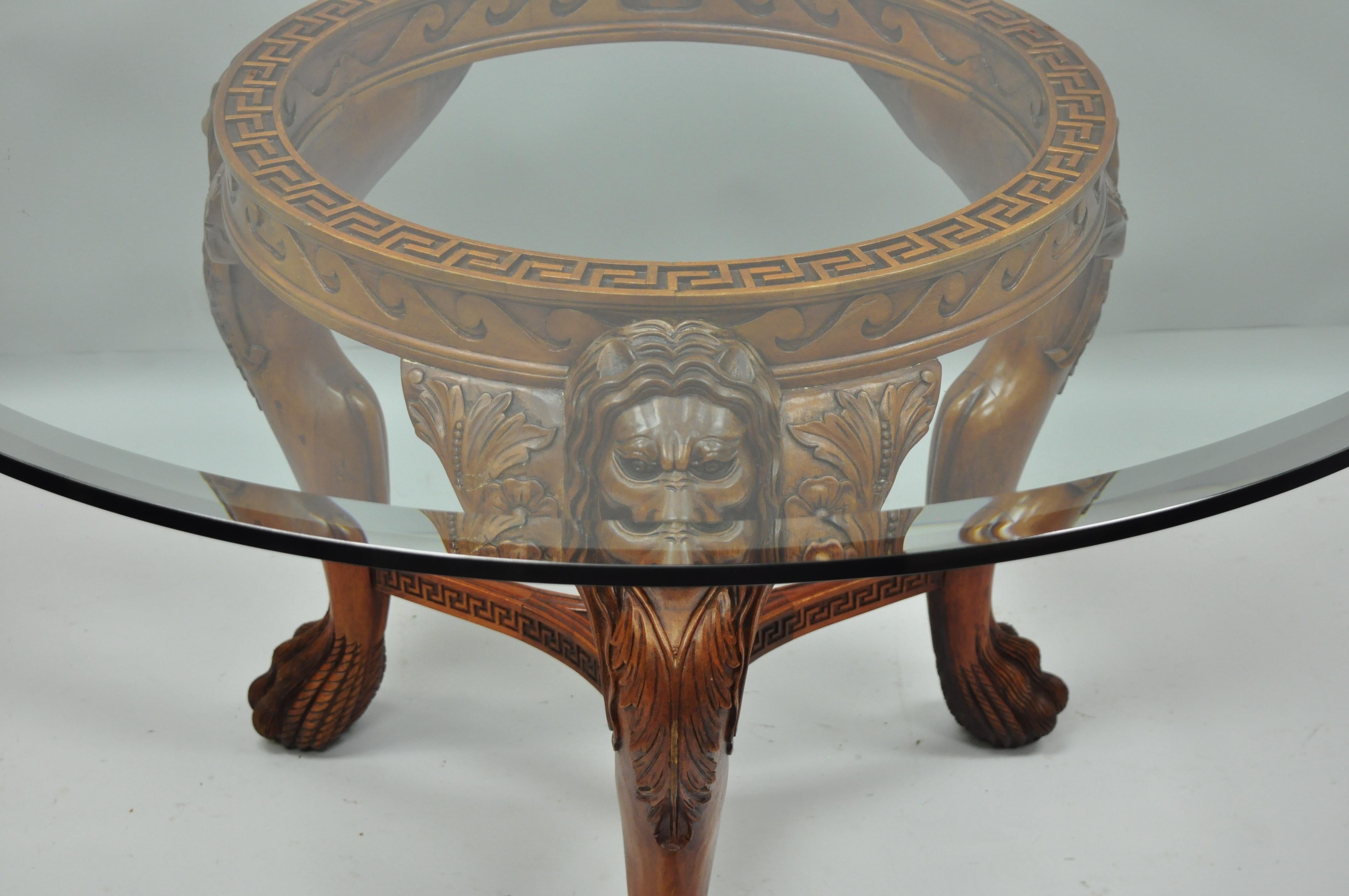 Chinese Chippendale style mahogany lions head claw feet pedestal dining table. Item features solid carved wood pedestal base with lions heads, hairy paw/claw feet, Greek key details, stretcher base, and bevelled glass round top, circa late 20th,