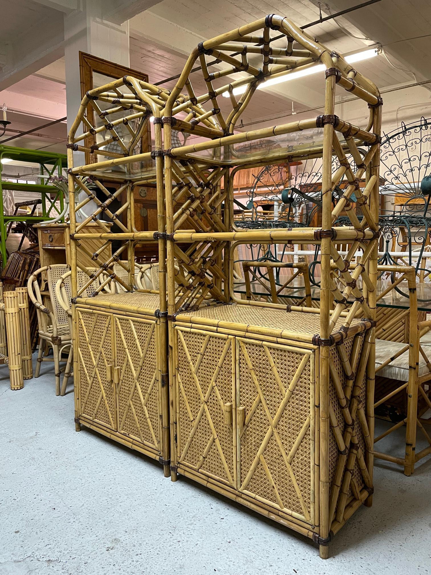 Pair of large rattan etageres feature Chinese chippendale fretwork and cane veneered shelves. Beautiful chinoiserie style pagoda tops and glass shelving. Contrasting leather strapping. One unit has a large open 2-space storage area behind double