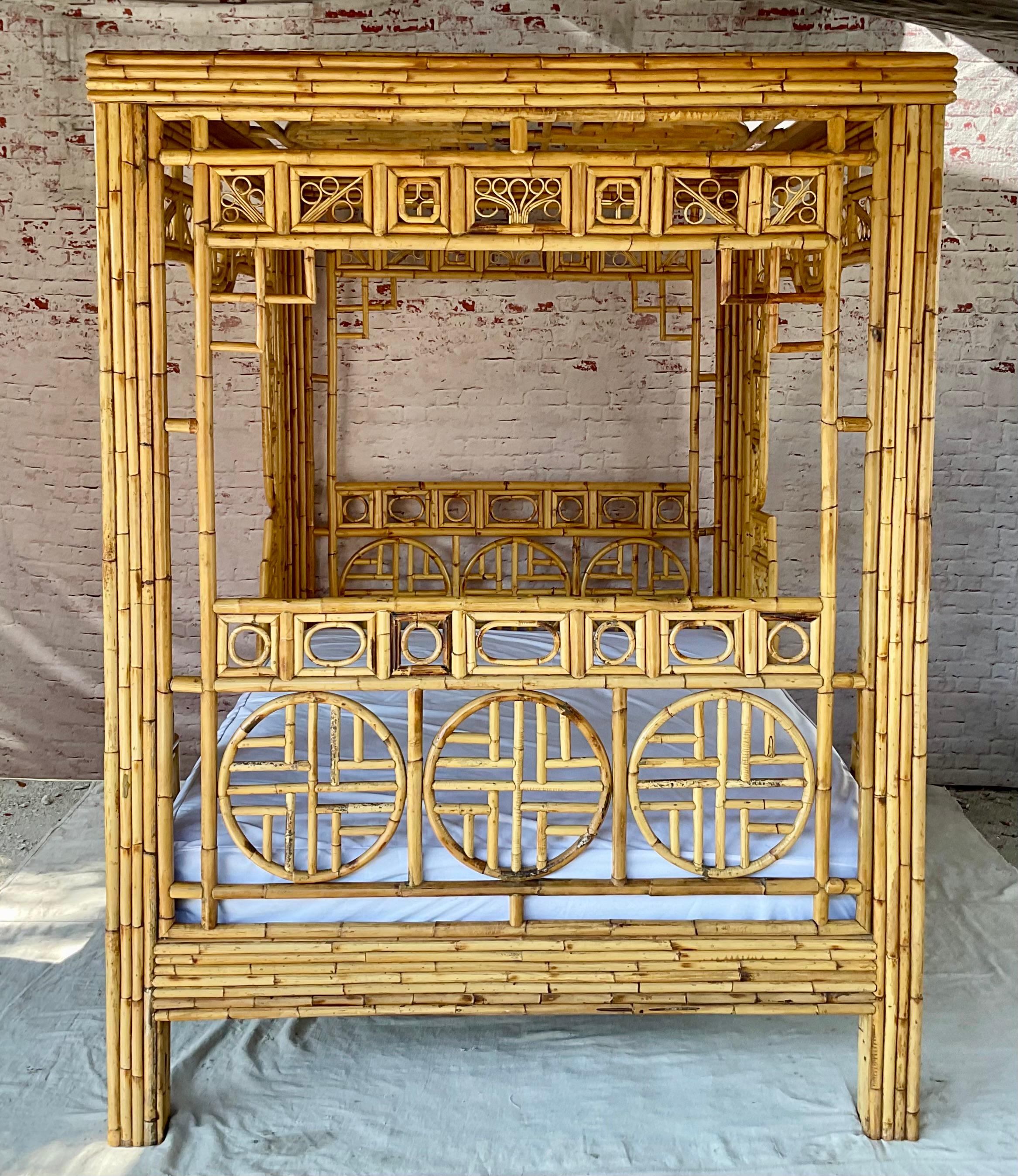 Mid-20th Century Chinese Chippendale Queen Size Rattan and Bamboo Canopy Bed in the Brighton Pavilion / Palm Beach Style. Bed features intricate fretwork panels with geometric and circular motifs that echo traditional Chinese architecture, giving