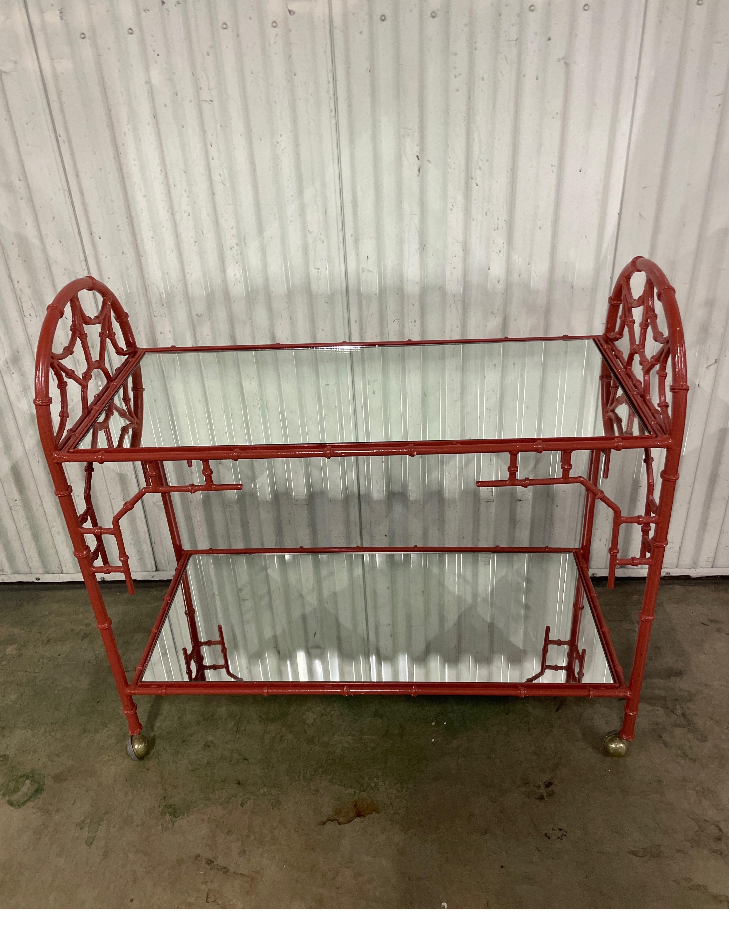 Vintage Chinoiserie bar cart with two mirrored shelves. Finished in a Chinese red lacquer. Beautiful fretwork design on all four sides. A very unique find.