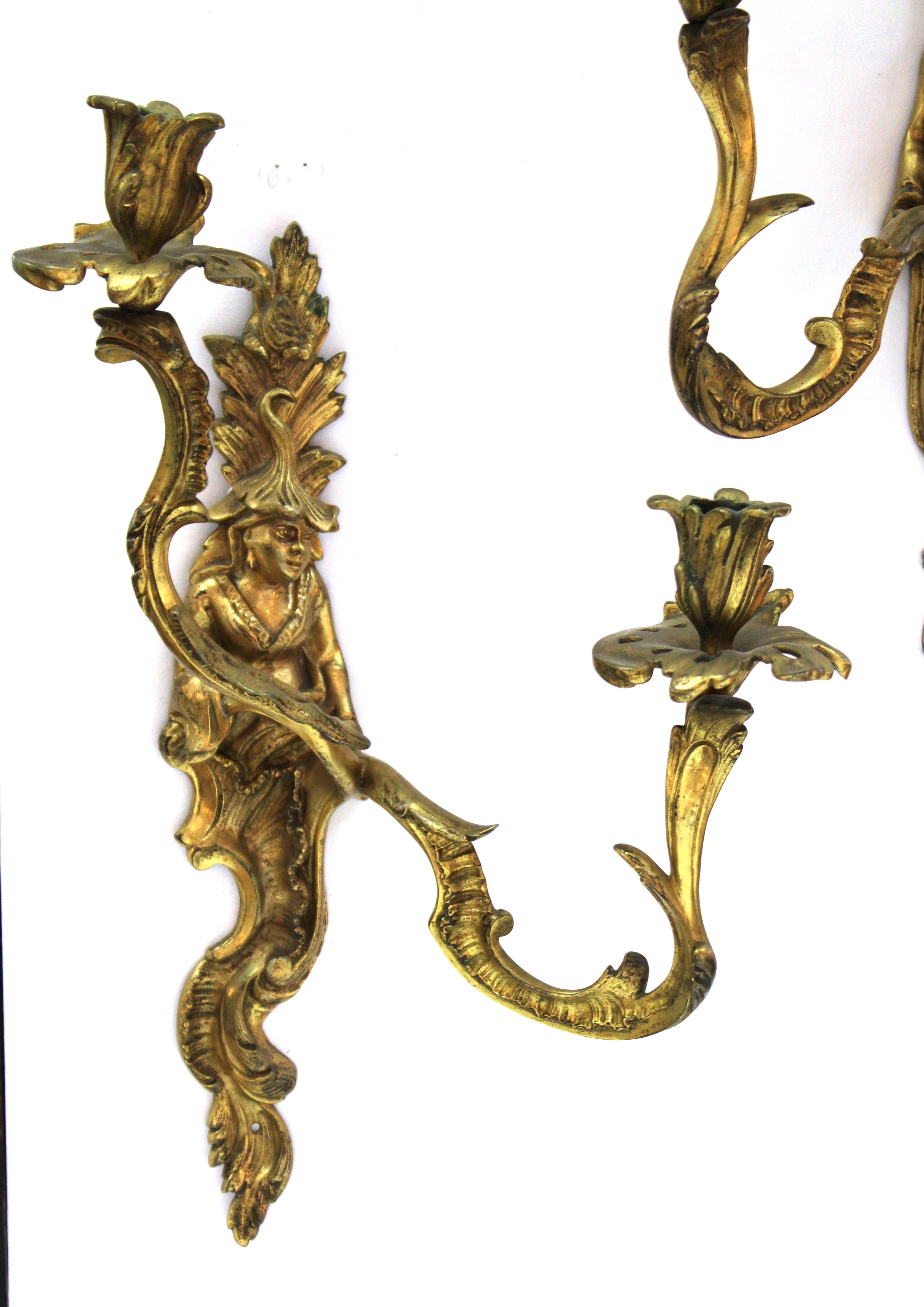 Chinese Chippendale style pair of bronze wall sconces with chinoiserie figures on the back plates. Elaborate foliage and a pair of rocaille arms complete each sconce. Made in the 19th century, the pair is in great antique condition with