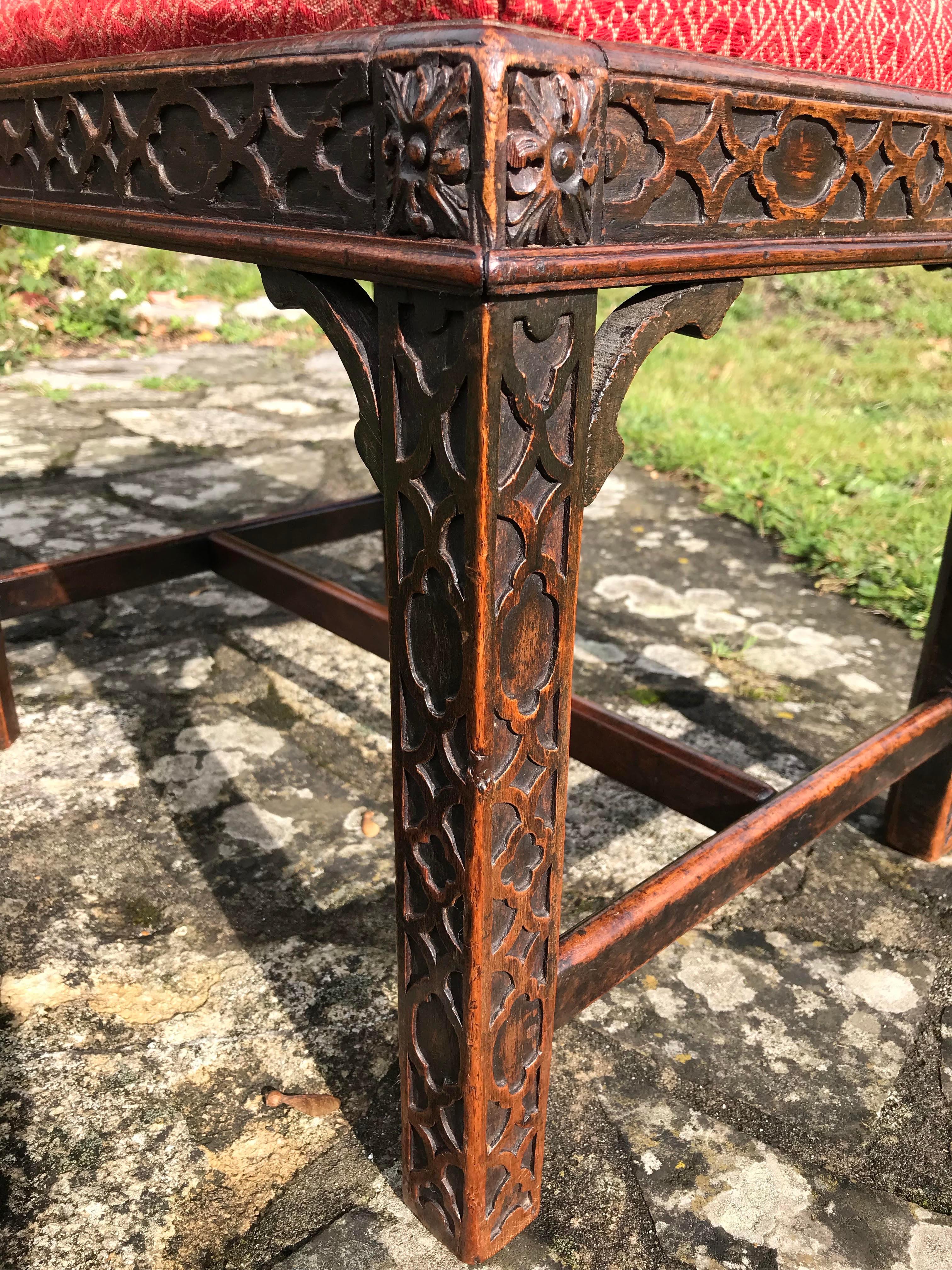 A sophisticated antique blind-fret carved mahogany stool in the Chinese Chippendale style.
19th century.

In excellent condition and sturdy in the joints.

Measures: 
L: 55 cm
W: 44 cm
H: 44 cm.

Nb. Blind-fret carving is encountered in many of