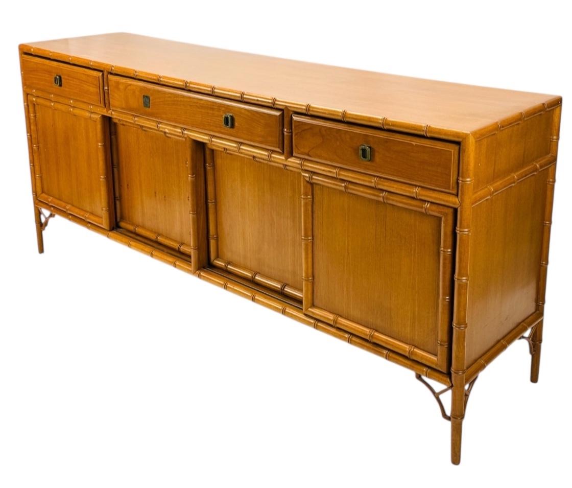 This is a 1970s Chinese chippendale style carved maple credenza. It has faux bamboo carved details to the frame and fretwork. Note the sliding doors and interior shelving. It is unmarked and in very good condition.