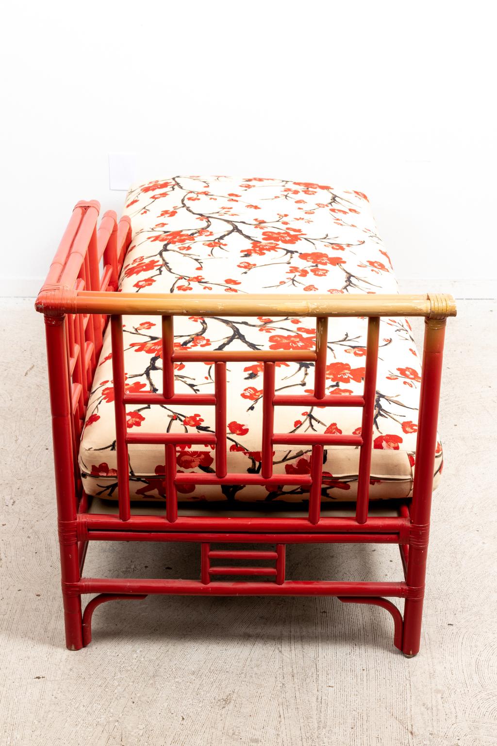 Chinese Chippendale style corner chaise lounge chair with painted bamboo frame and upholstered red flower fabric. The piece is further detailed with Chinese Chippendale style fretwork panels. Please note of wear consistent with age including paint