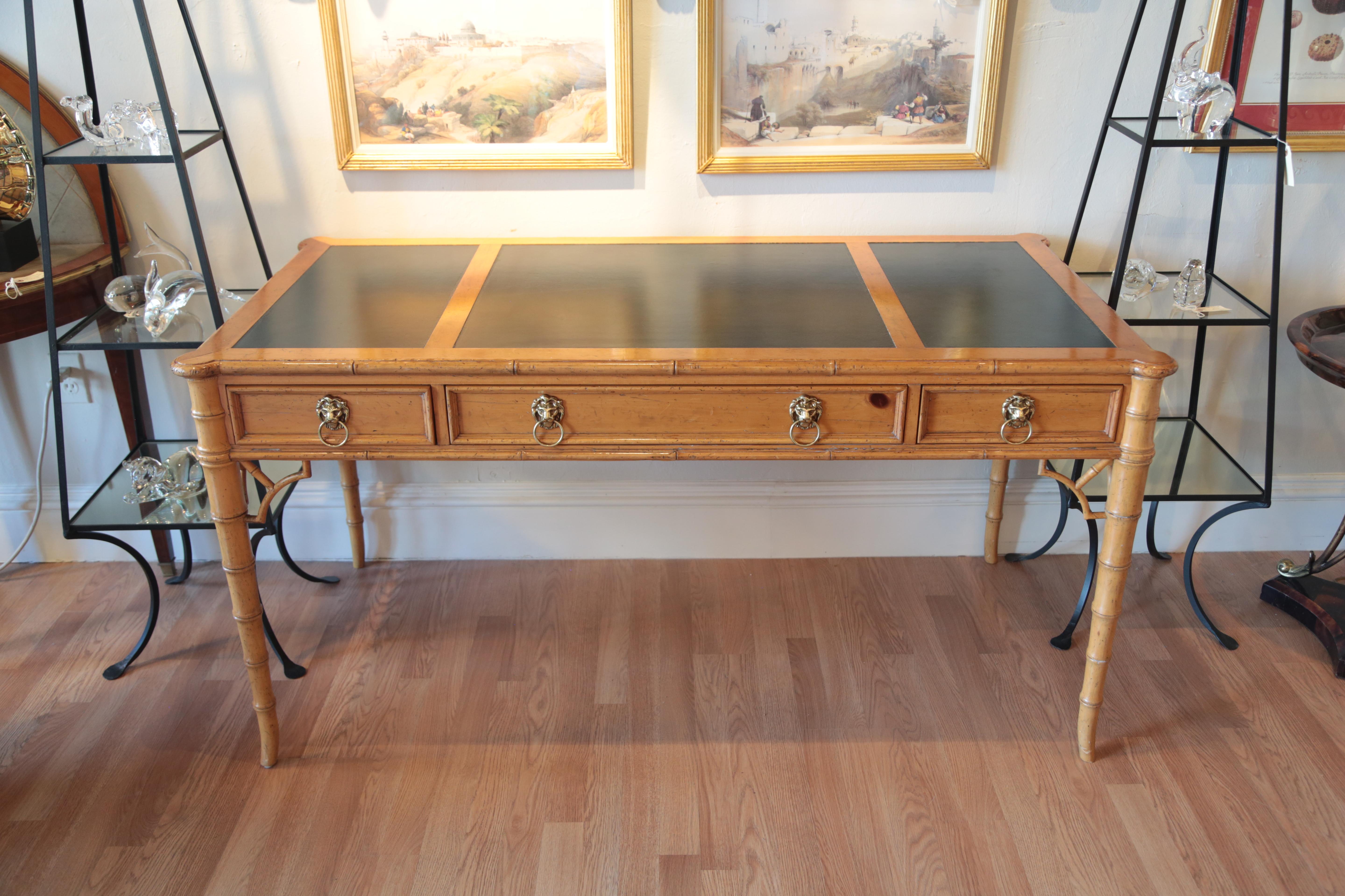 Chinese Chippendale style desk with dark green leather inserts on top by Baker Furniture Co. Lion's head ring pulls on drawers. Faux bamboo style legs.