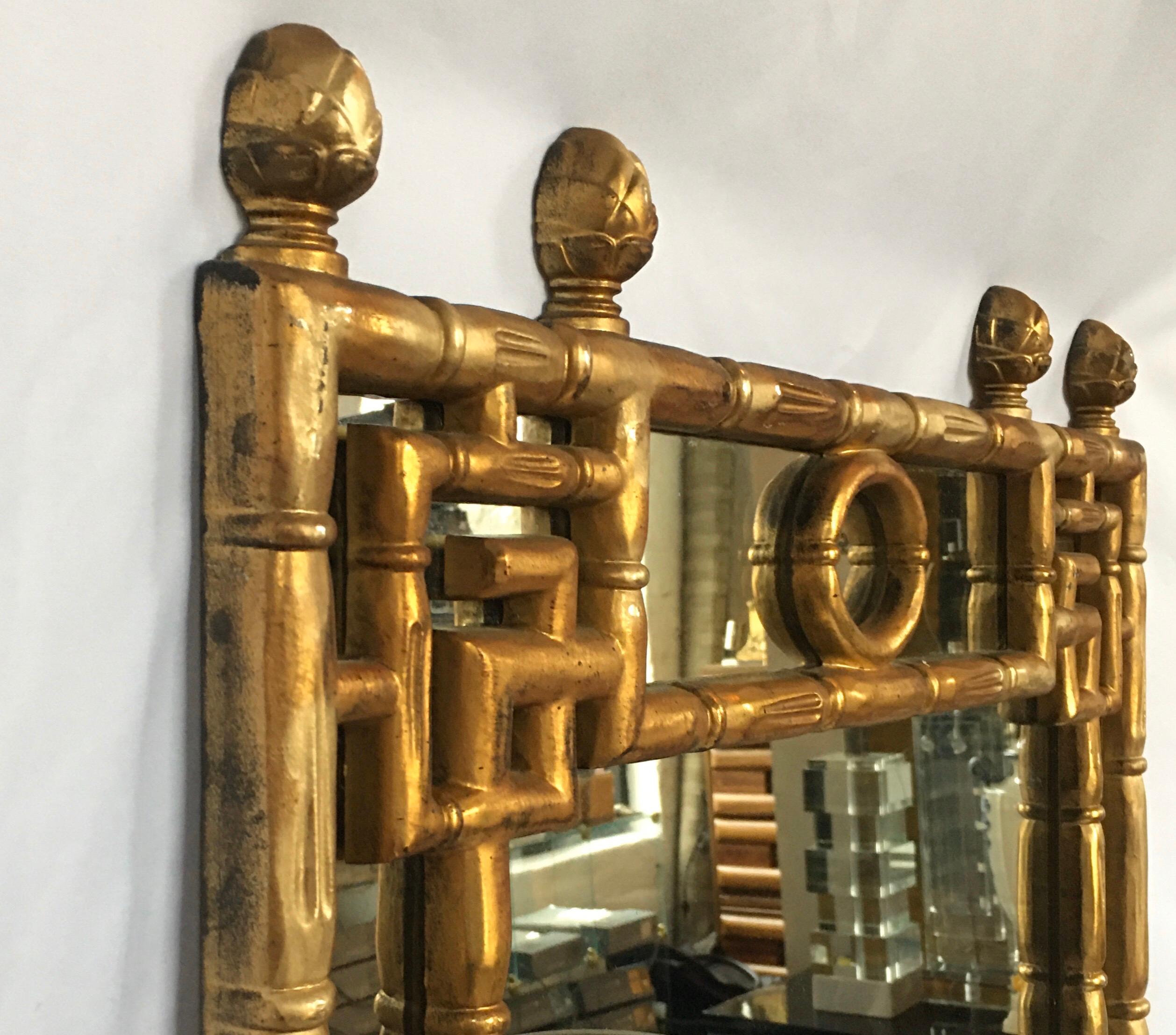 Midcentury Chinese Chippendale style wall mirror topped with four finial decorations. Faux bamboo frame features Greek key designs and original metallic gilt gold finish. Frame constructed of natural cellulose composition and wood fibers.