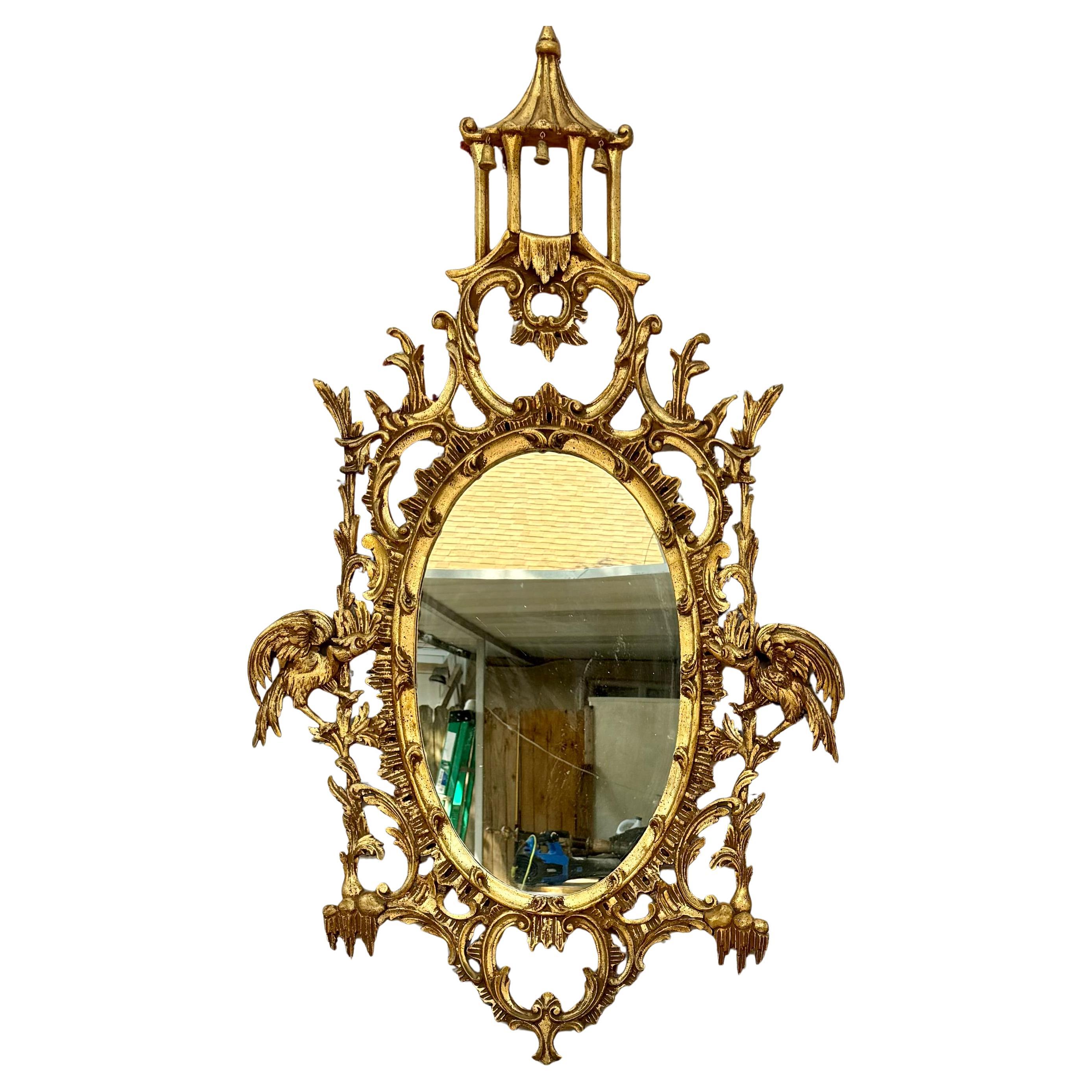 Grazioso specchio da parete in legno dorato dei primi del Novecento. Lo specchio ovale è realizzato in  Lo stile cinese Chippendale è caratterizzato da intricati intagli e dettagli ornamentali, con uccelli esotici e una pagoda in cima. 