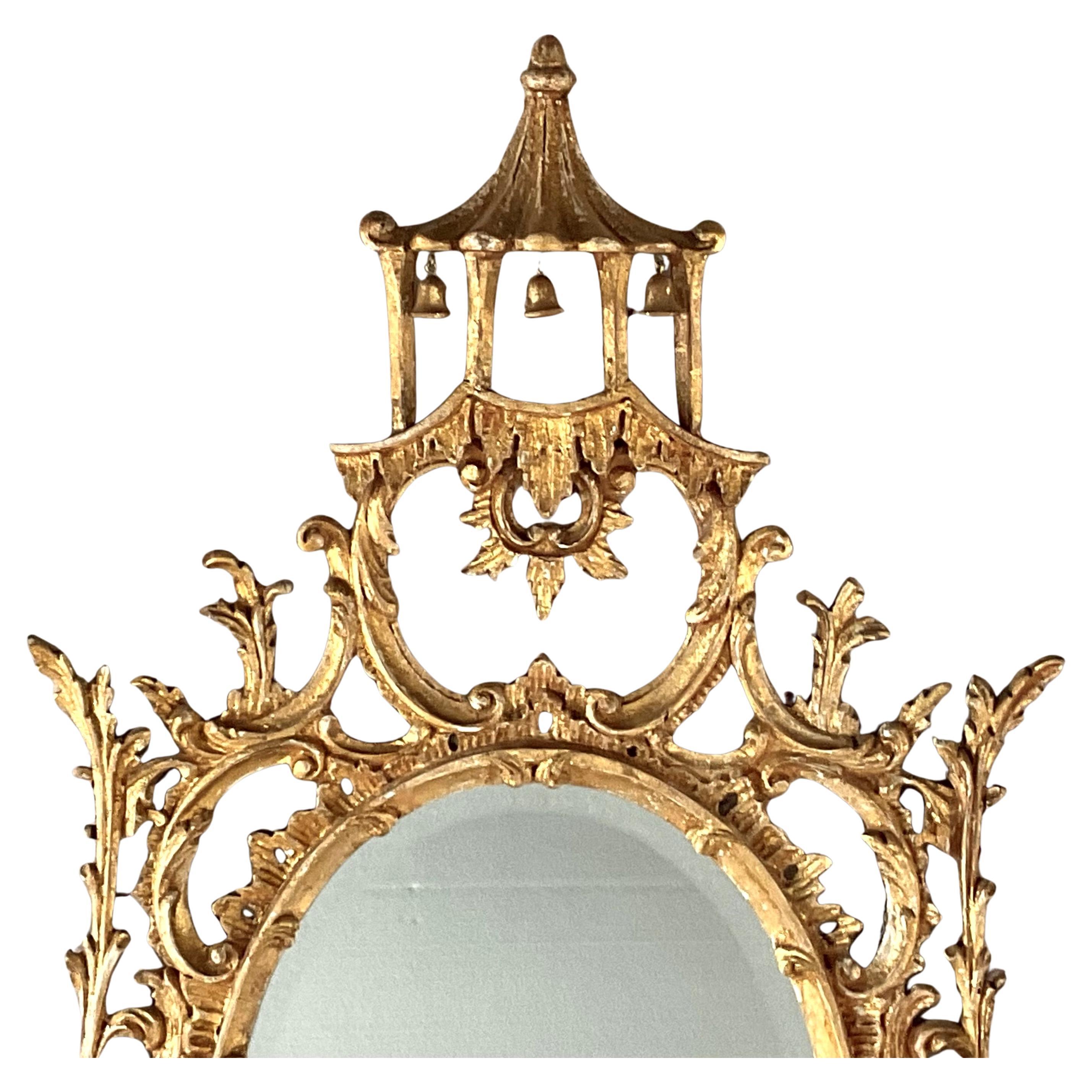 Grazioso specchio da parete in legno dorato dei primi del Novecento. Lo specchio ovale è realizzato in  Lo stile cinese Chippendale è caratterizzato da intricati intagli e dettagli ornamentali, con uccelli esotici e una pagoda in cima. 