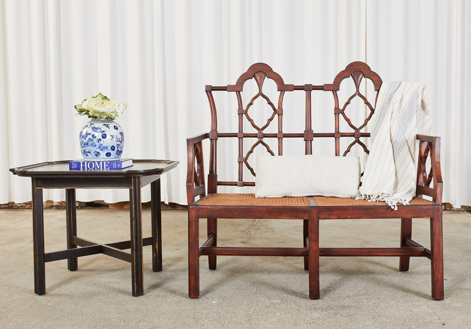 Distinctive mahogany bench seat or settee hand-crafted in the Chinese chippendale taste. The bench features a caned seat and arabesque quatrefoil designs on the back and sides. The settee has a rich finish that showcases the beautiful wood grain