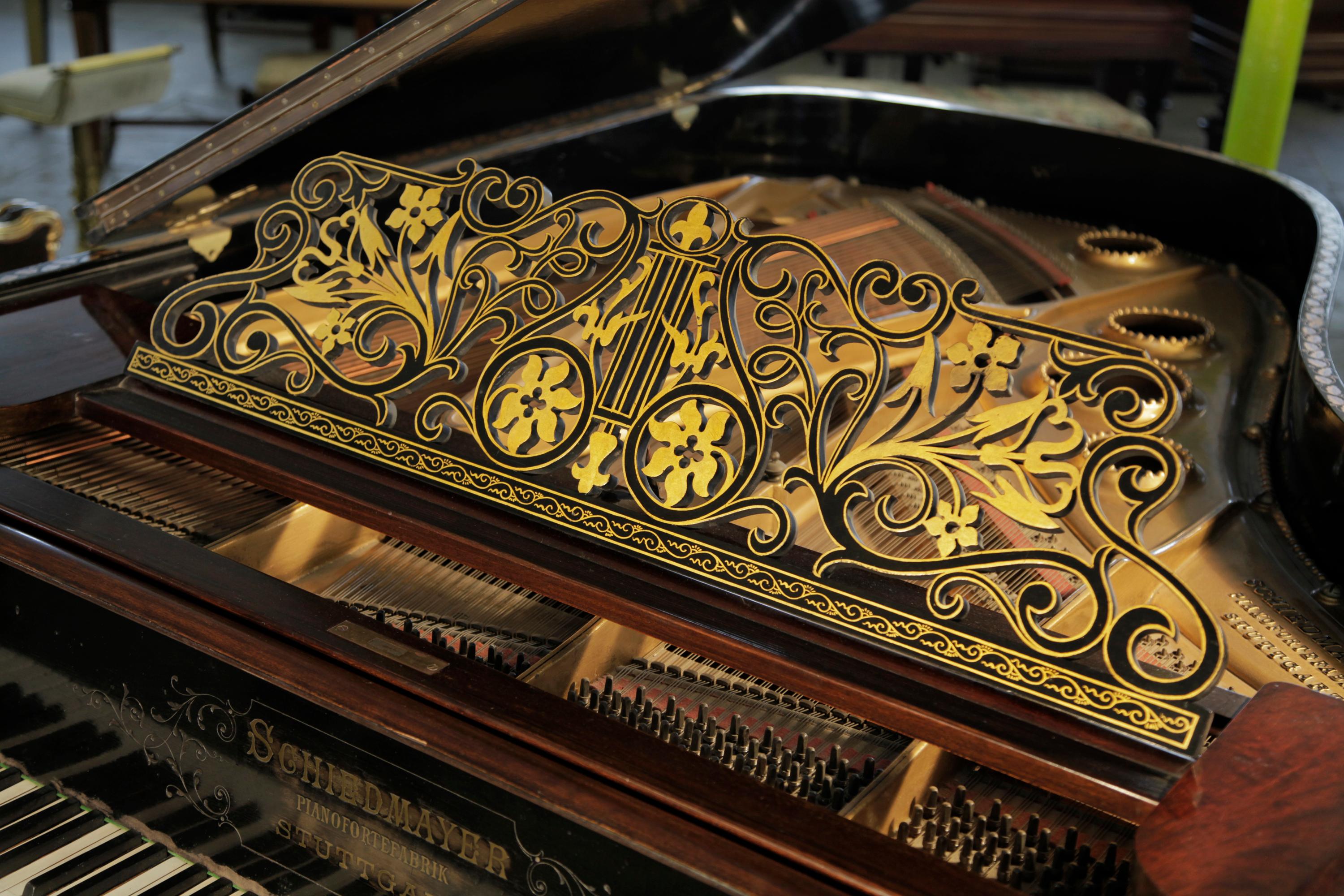 Chinese Chippendale style, 1899, Schiedmayer grand piano with a flame mahogany case and Malborough legs with applied fret carvings. Cabinet features oriental scenes in embossed Japanning with gilt ornament.
The pierced, filigree music desk is in a