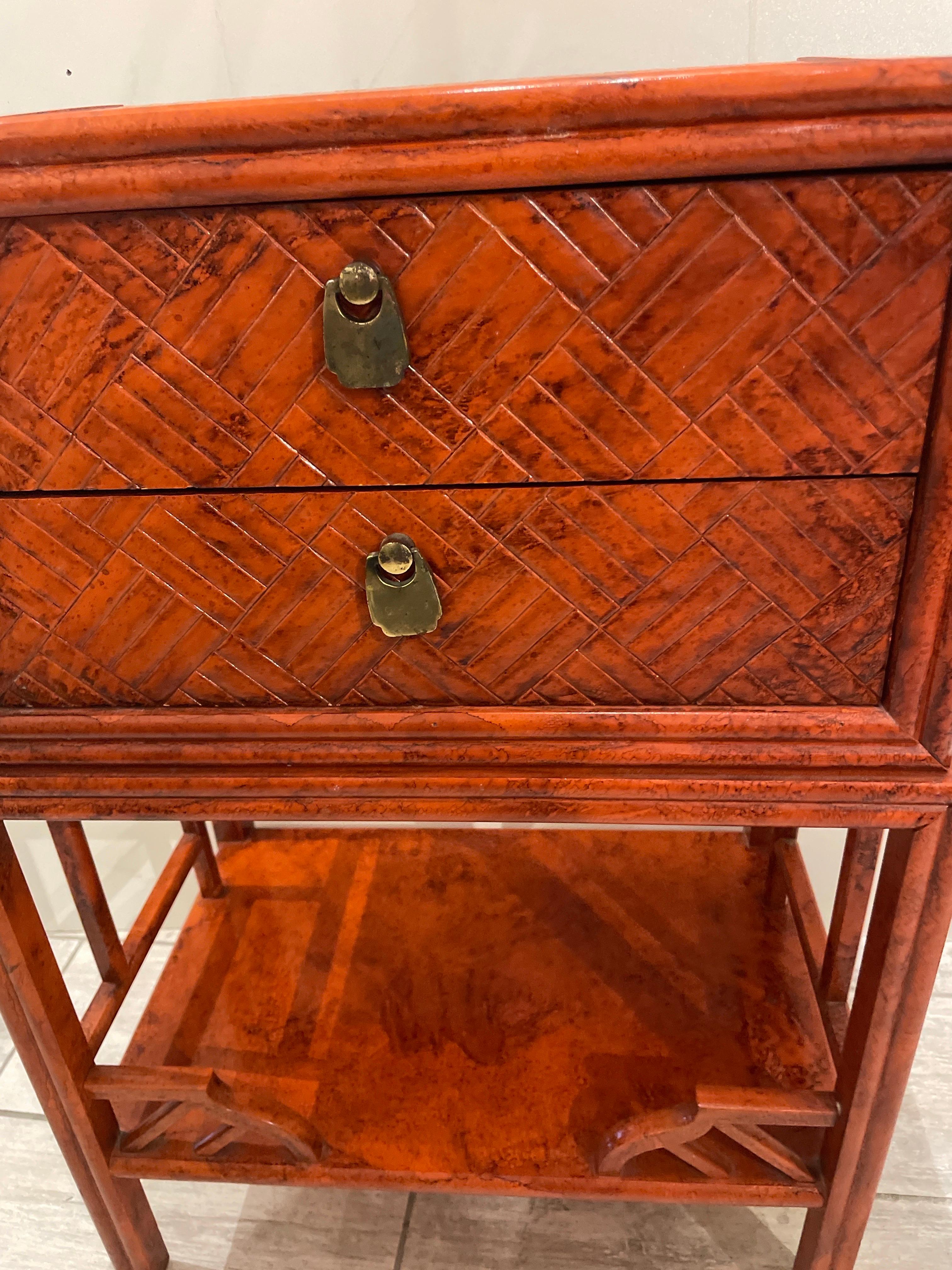 Vintage Chinese Chippendale Style two drawer side table with bottom shelf. Finished in a cinnabar color on a basket weave motif. A very versatile piece.
Great side Table, nightstand, or great bathroom storage piece.