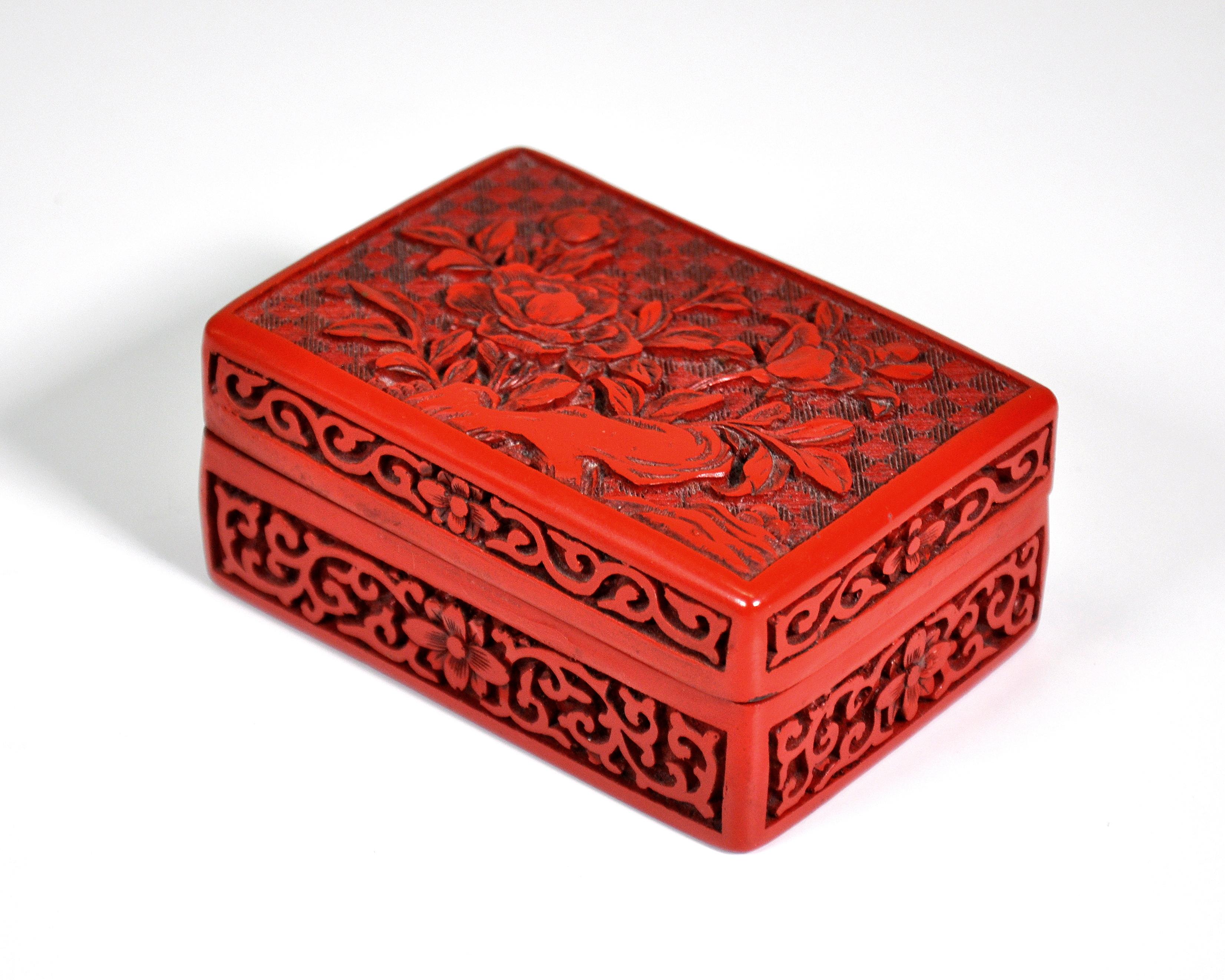 Vintage Chinese rectangular vanity, jewelry or trinket red cinnabar box with carved lid depicting flowers, leaves and geometric motifs with black lacquer interior.