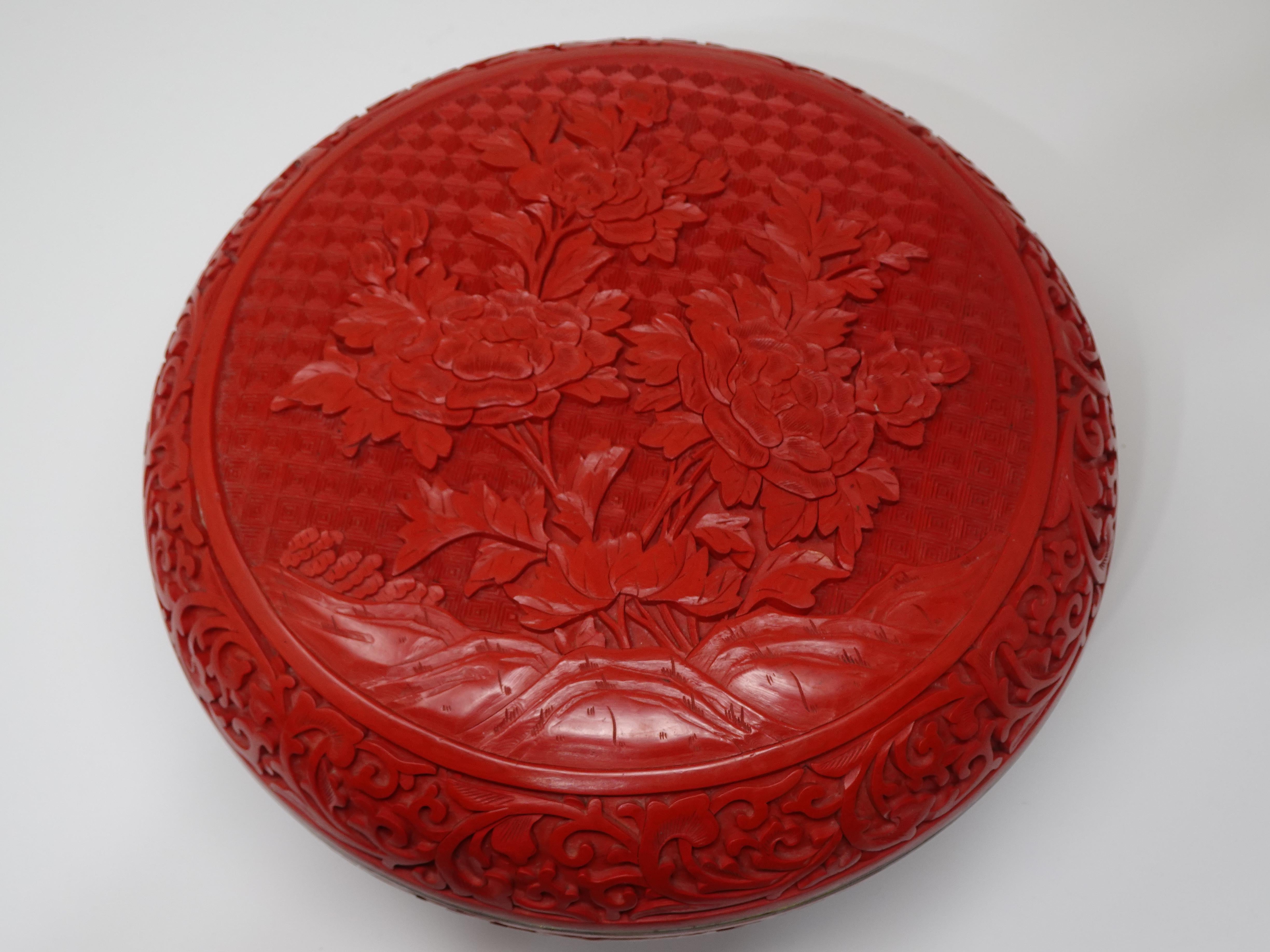 A well crafted Chinese Cinnabar lidded box with heavy detailed carving to the sides and lid, the lid has flower motif's looking like Chrysanthemums. Brass to the edge of the lid, box and base we think 1930's export just a nice and beautiful object.