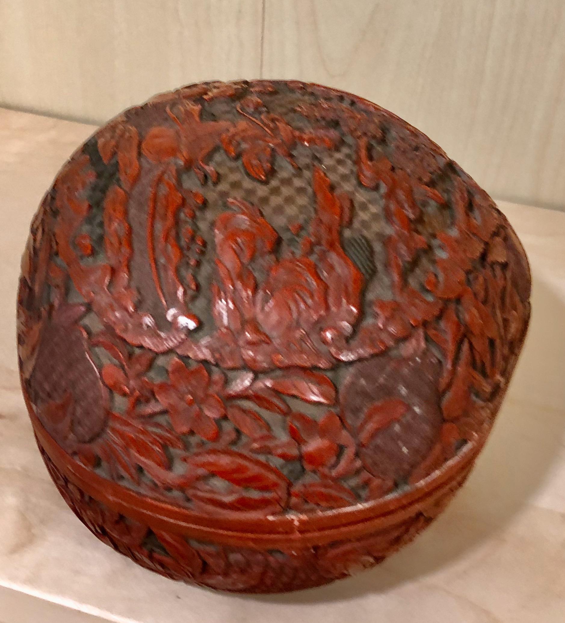 Chinese cinnabar very finely carved box circa late 18th or early 19th century. The multiple lacquered layers of red over black over amber, the cover carved with a scene of Kwan Yin in a rockery garden within a cartouche border of repeating winged