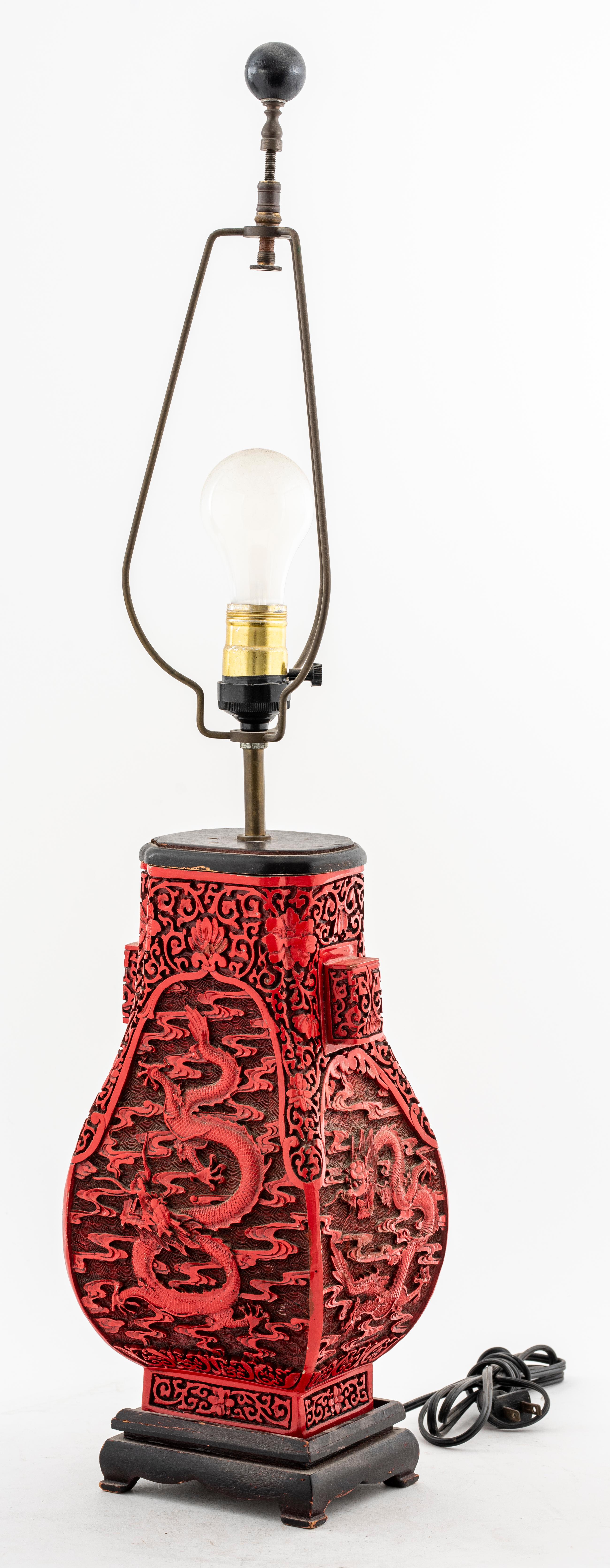 Chinese cinnabar lamp with a dragon motif & floral design, on a wooden base.