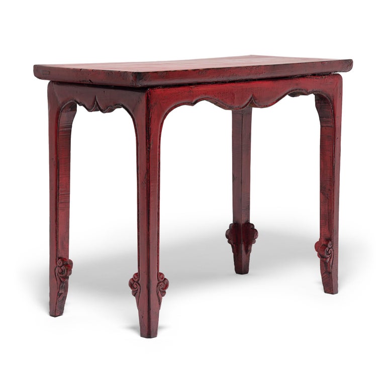 The sculptural form of this early 20th century side table is elevated by a brilliant cinnabar-red lacquer finish. The waisted table features a floating panel top, straight legs, and a curvilinear apron traced by a finely beaded edge. The legs end in