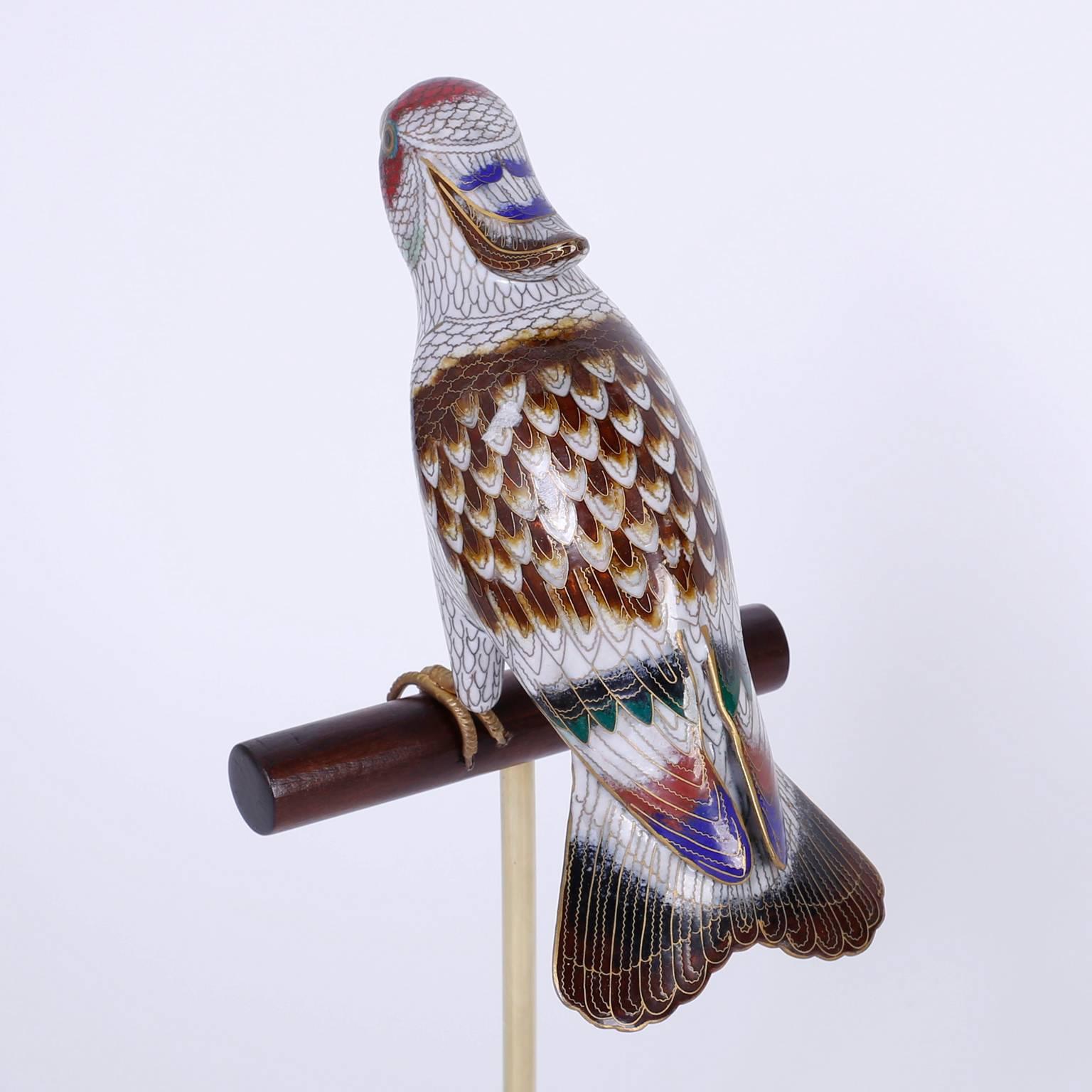 Raffinato pappagallo o uccello cinese sapientemente decorato con smalto su ottone, presentato su un trespolo in legno personalizzato e un supporto in lucite.