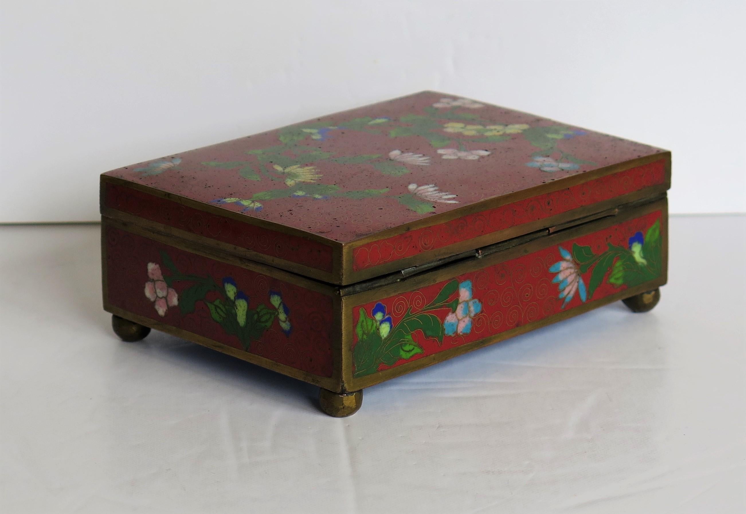 This is a good Chinese cloisonné box with a hinged lid and floral decoration which we date to the late Qing Dynasty, circa 1900.

The rectangular box is raised on four small bun feet and has a hinged lid.

The decoration is on all four sides of