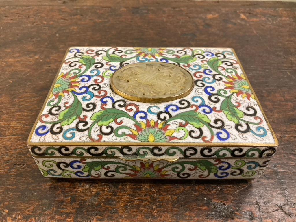 Circa 1900 Chinese box decorated with green, blue, red and yellow floral design set against a white background. The top with a carved white jade floral medallion. The apple green enameled interior divided into four compartments. Resting on four ball