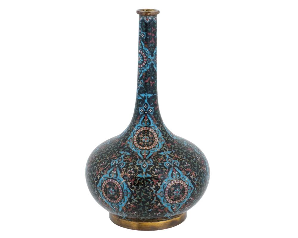 A Chinese enamel over brass vase. The vase has a globular shaped body and a tall neck. Adorned with polychrome enamel in foliage and geometric motifs made in the Cloisonne technique. Has a round shaped gilt base. Circa: the first half of the 20th