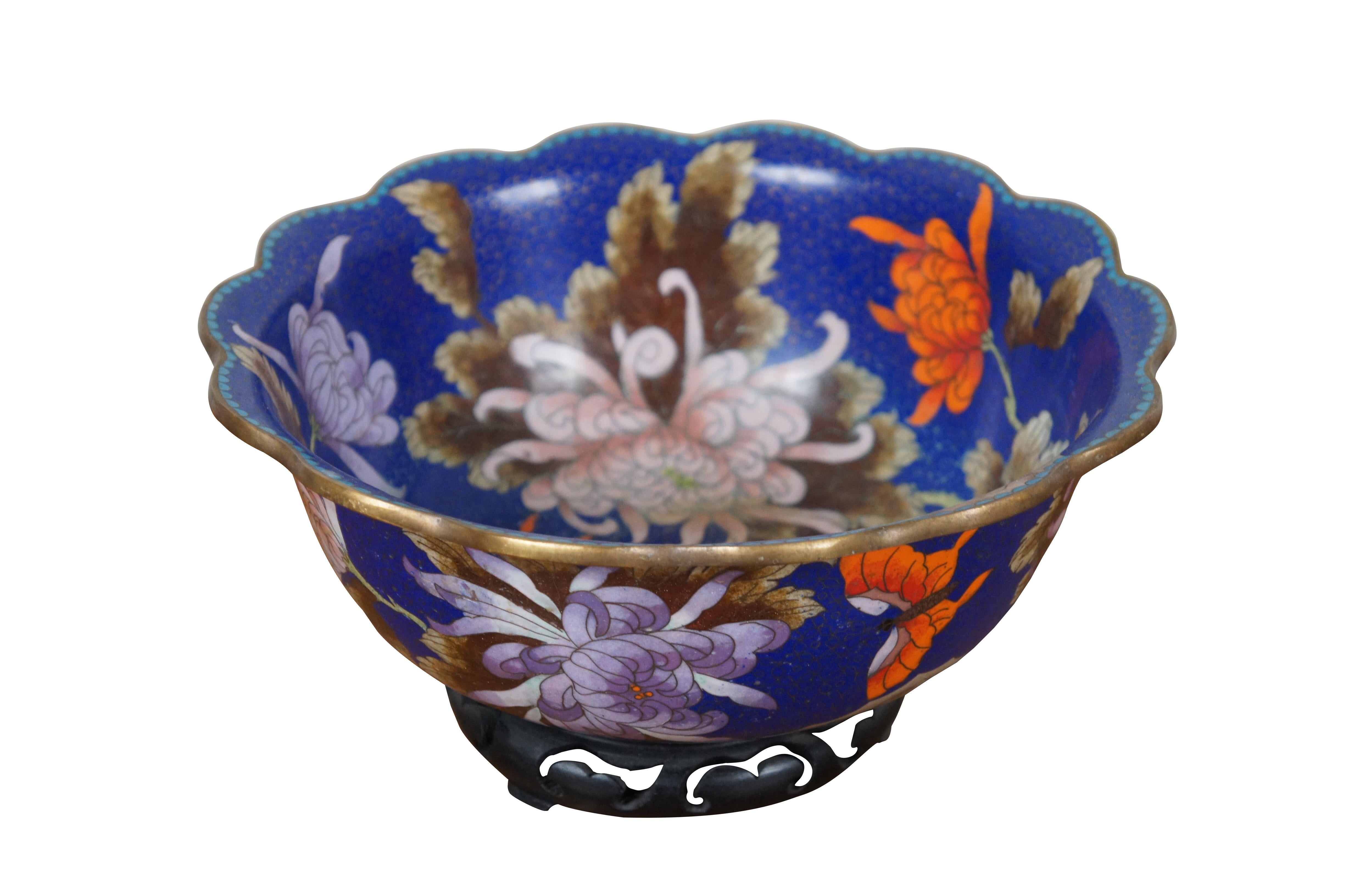 Vintage Chinese cloisonne bowl / centerpiece with scalloped rim, decorated with pink and orange chrysanthemums, brown and green leaves, scalloped turquoise trim, and orange butterflies on a floral patterned background of deep sapphire blue. Includes