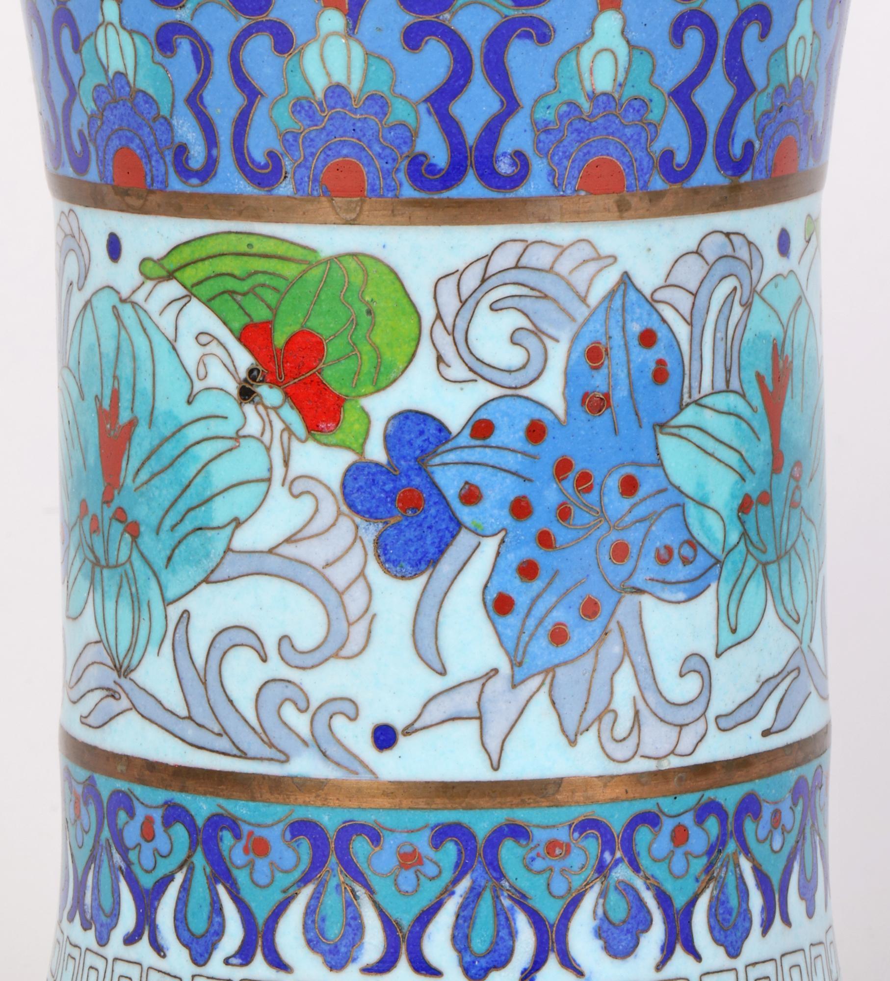 A stylish trumpet shaped waisted cloisonne vase decorated with stylized floral patterning and dating from the early to mid-20th century. The vase made from brass metal stands on a wide round base slightly recessed and finished in typical turquoise