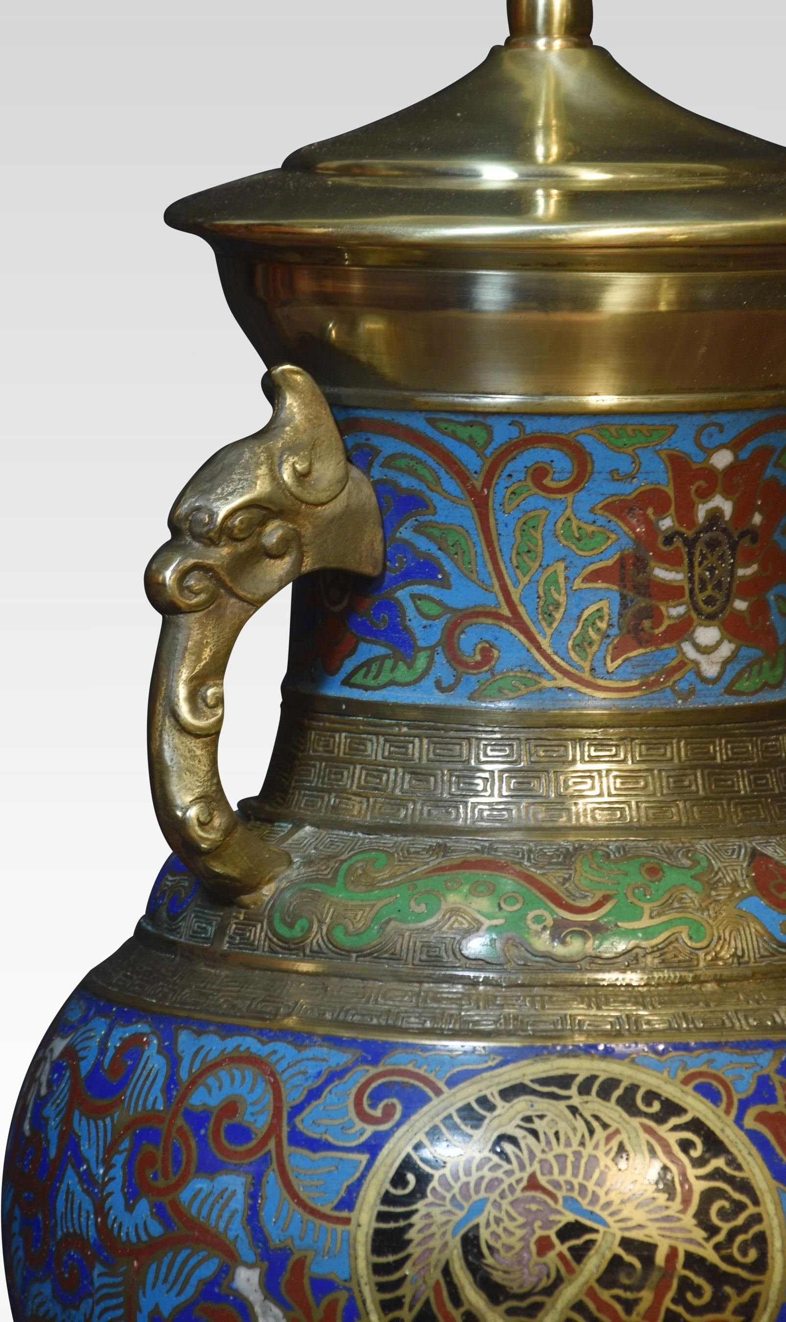 Chinese cloisonne twin-handled lamp base with panels of foliate motifs and roundels featuring dragons and phoenixes, between Greek key borders, the twin handles partially modelled with dragon heads. Raised up on pierced ebonies