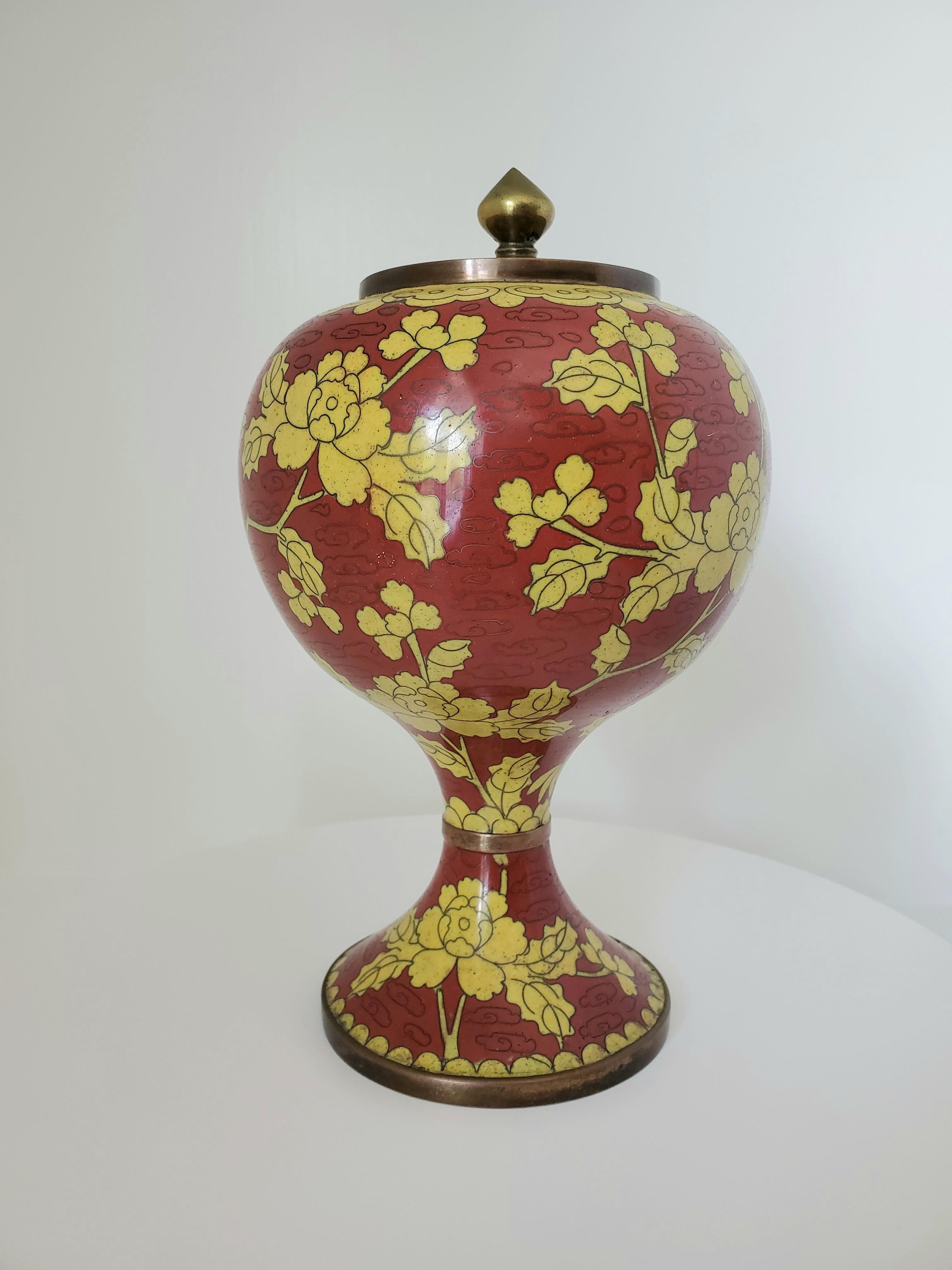This lovely and unique Qing Dynasty Cloisonné urn with lid is approximately 125 years old and is shiliuzun or pomegranate shaped with a flared stem base. The pattern consists of a mustard coloured floral motif on a red field with stylized clouds or