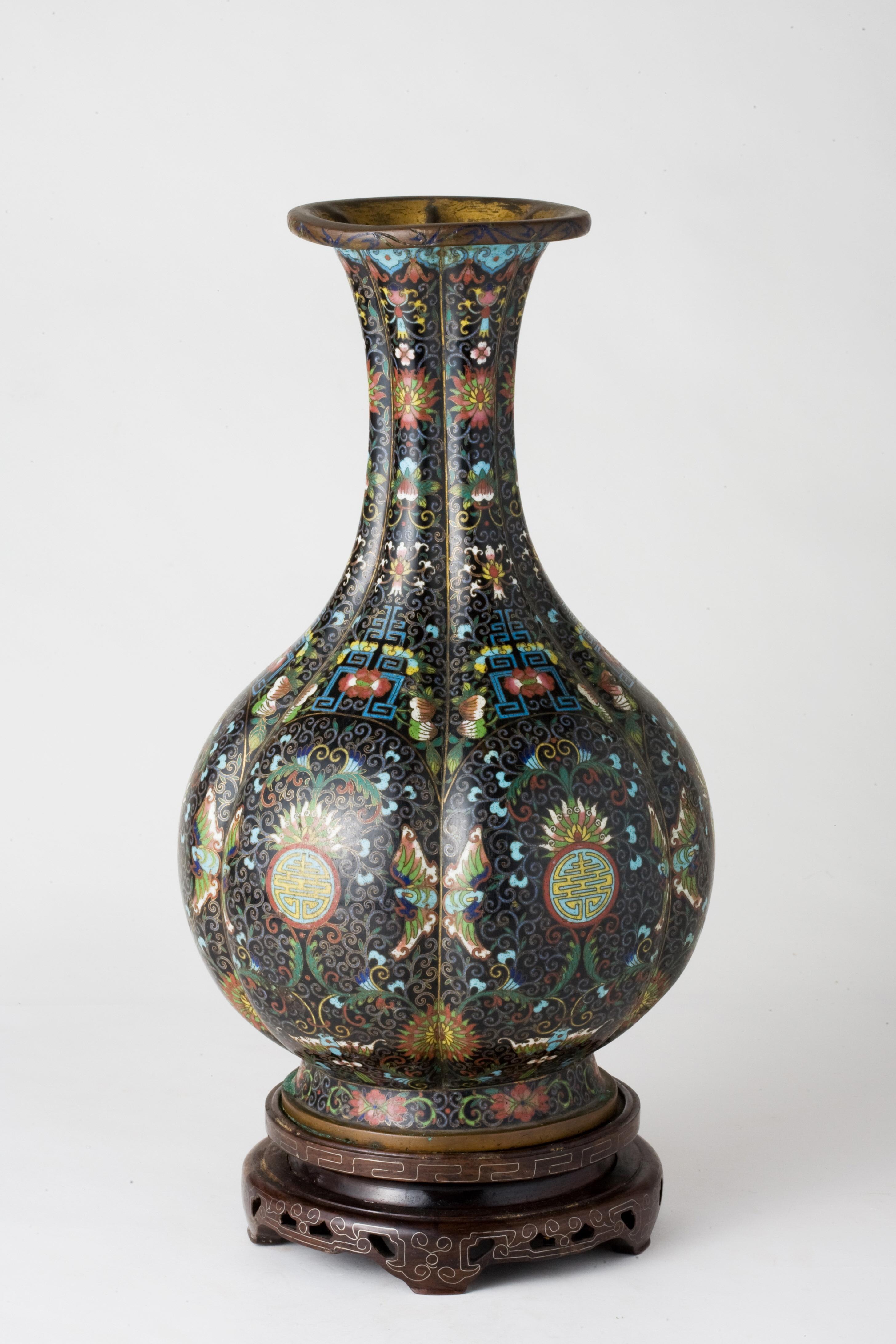 Cloisonné enamel vase of baluster form and lobed sides decorated with foliage and flowers on a black background, gilt copper neck and base. Around 1900

Period: Qing Dynasty
Type: Vase
Medium: Cloisonné Enamel
Height: 38.0 cm
Provenance: The piece