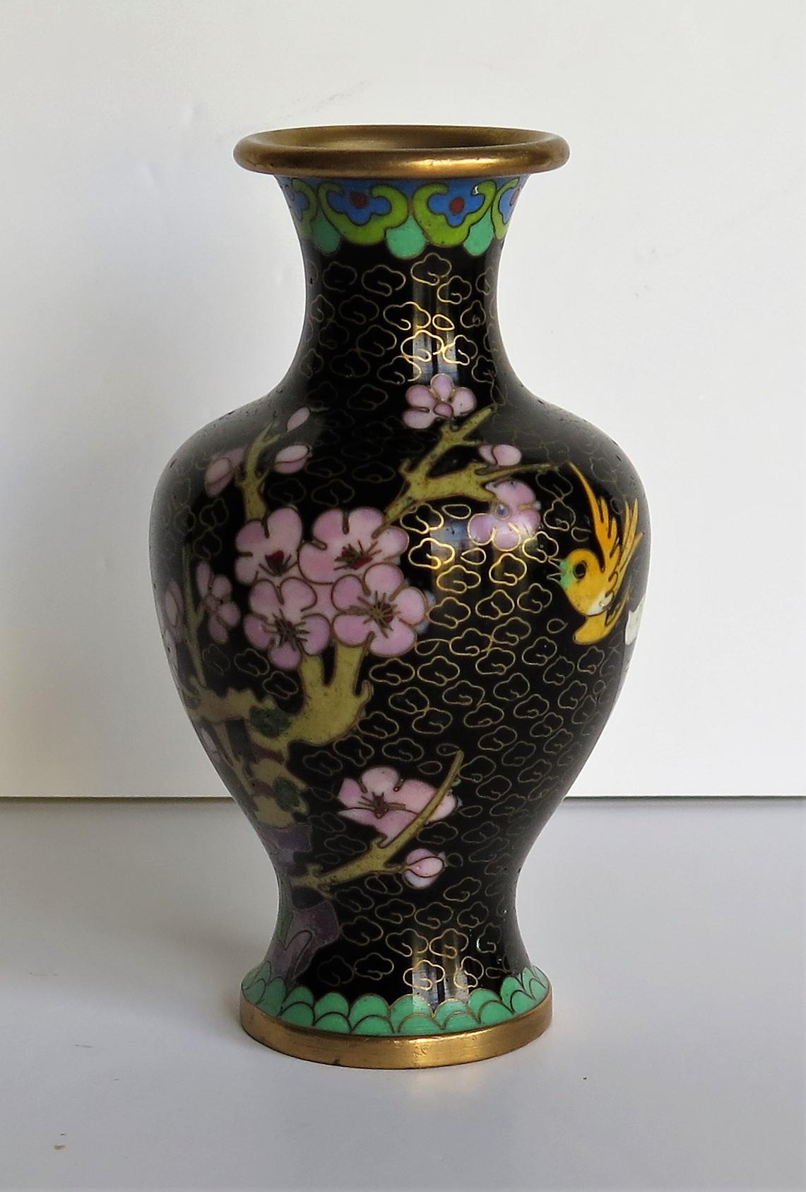 This is a very decorative cloisonné vase, made in China and dating to the mid-20th century.

The vase has a good baluster shape. It is beautifully made of a bronze alloy with rich colorful enamels, set into a black ground.

The decoration shows