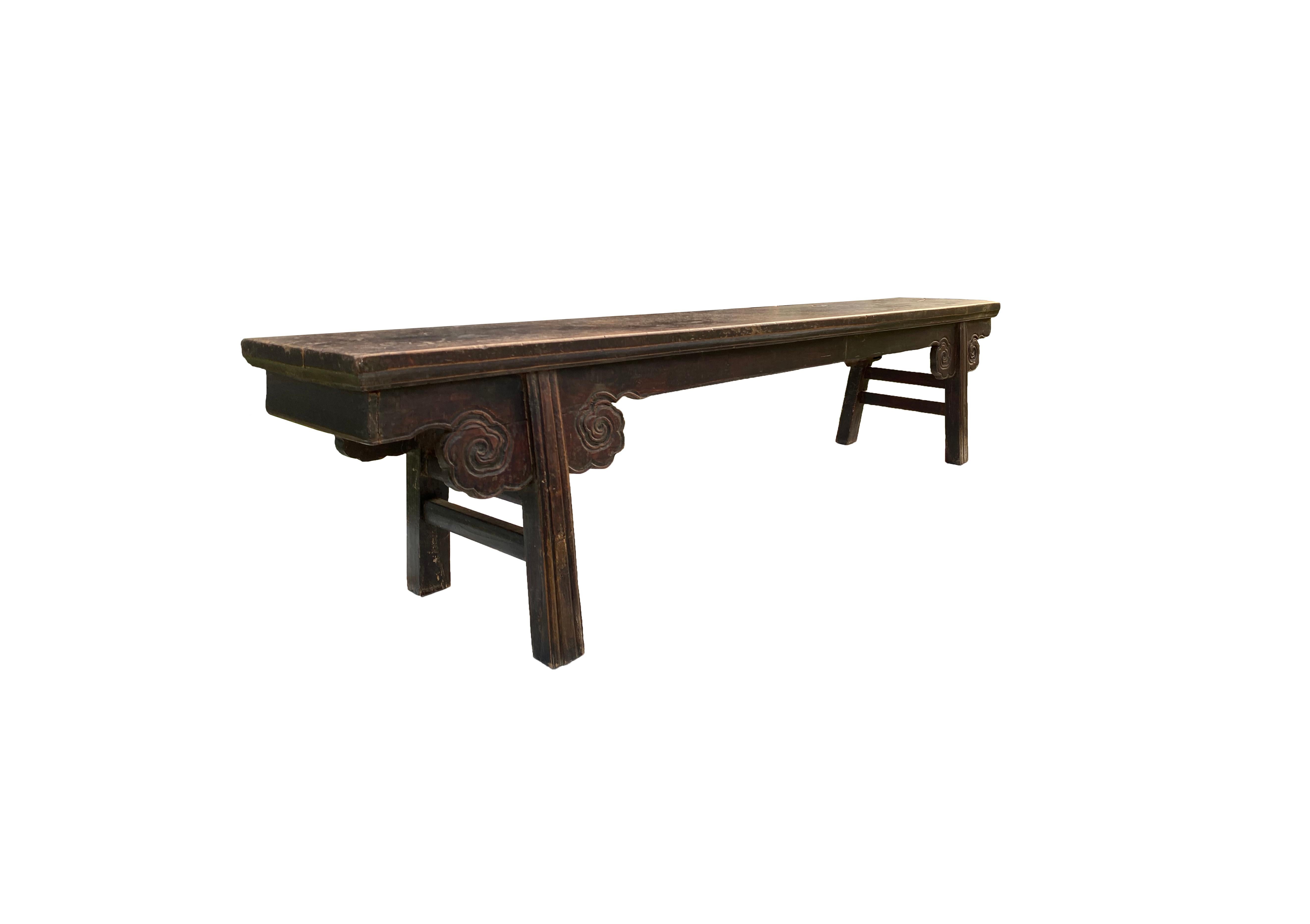 This Chinese cloud pattern long Bench from the Qing Dynasty features wonderfully carved cloud spandrels, straight legs with double stretchers and a solid top. It features a more than centuries old lacquer finish and age related patina and textures.