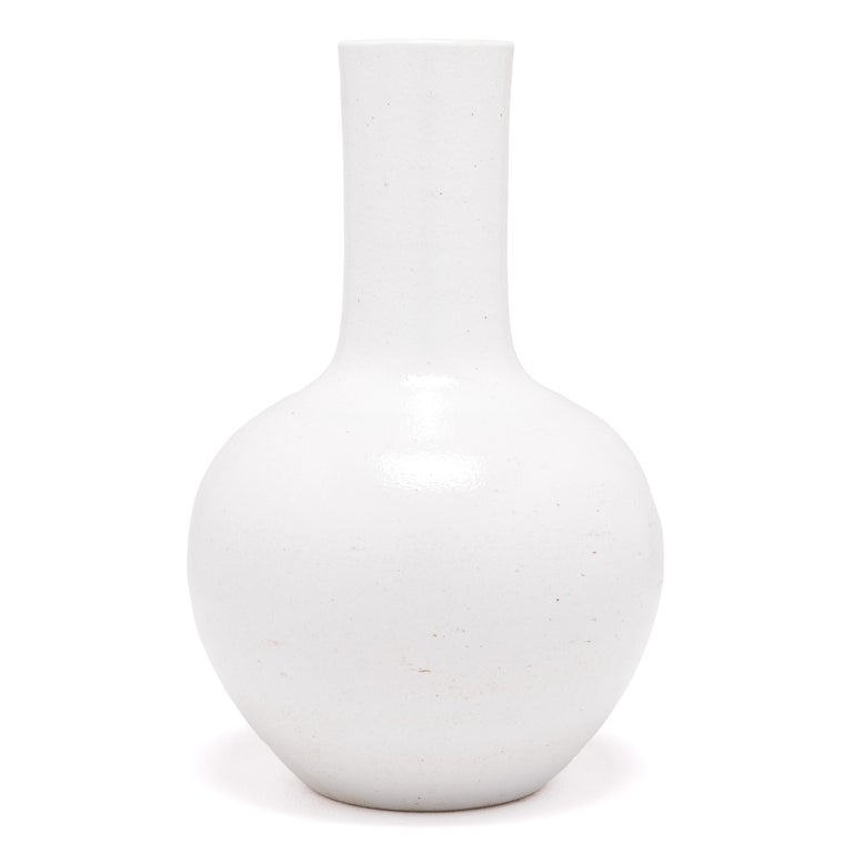 Drawing on a long Chinese tradition of monochrome ceramics, this austere long-necked vase is glazed in serene, cloud-inspired white. Crafted in Jiangxi province, local ceramists reinterpreted this very traditional shape with clean lines and an