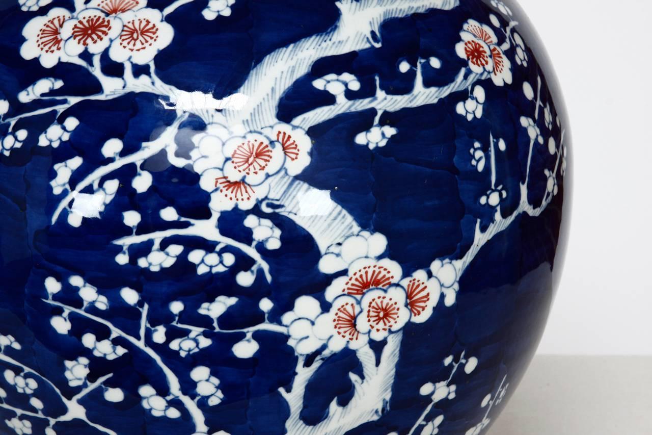 Remarkable Chinese cobalt blue and white stick neck vase featuring pink and white prunus decoration over a deep blue ground. The vase has two concentric circles on the base in the Kangxi Period style but probably later 20th century Chinese export.