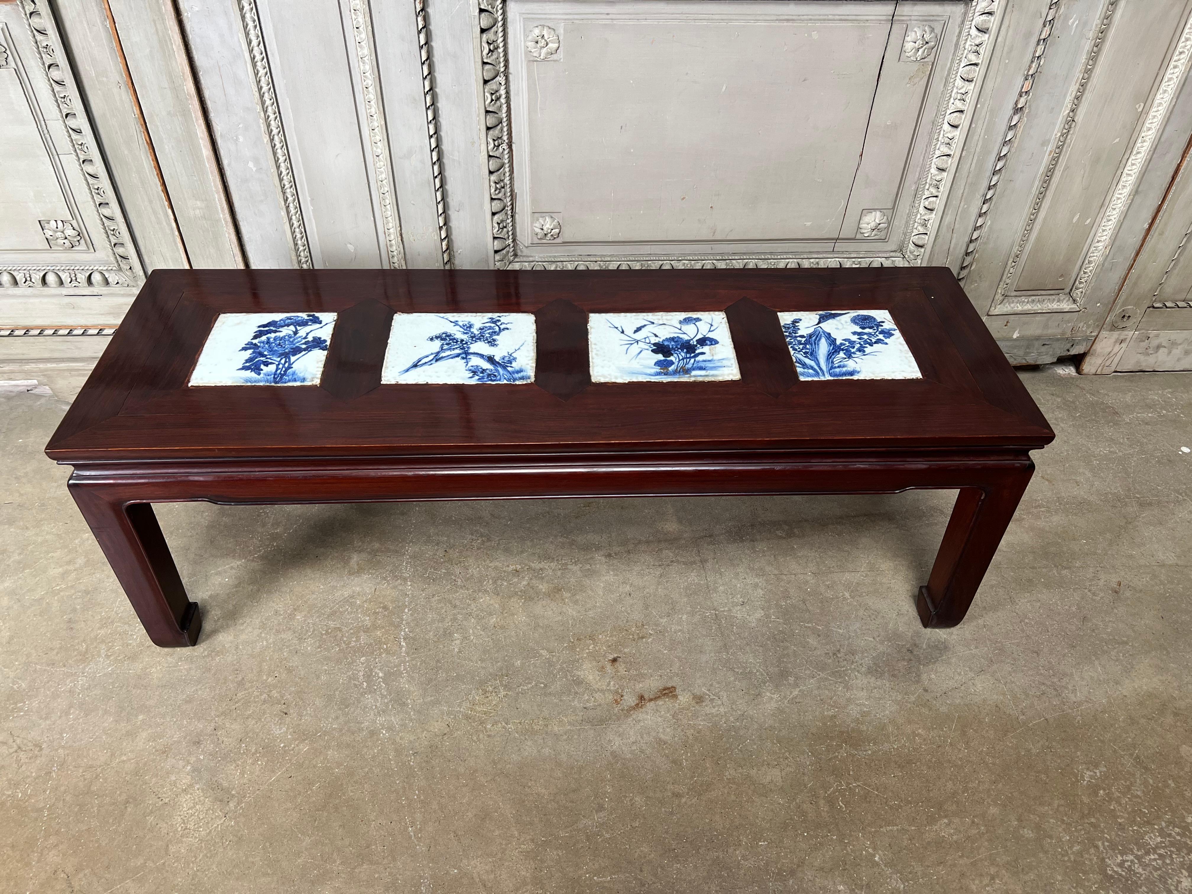 A mid 20th century Chinese rosewood Ming style coffee table with four large 19th century inlayed Chinese blue and white porcelian tiles. This very decorative cocktail table is a great size for a tight space. It would easily work in many different