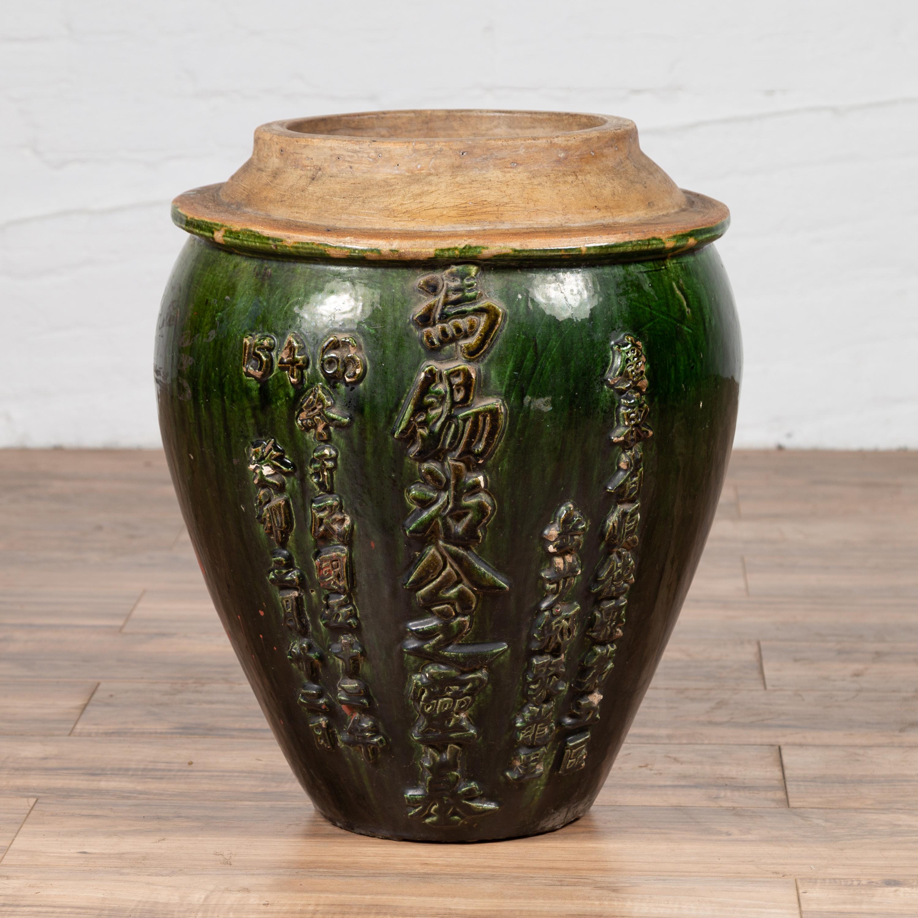 A Chinese green glazed water jug with unusual design and calligraphy. Born in China, this green glazed water jug captivates with its striking design and artistic elegance. The jug features a richly hued green glazed body, topped by a flaring neck
