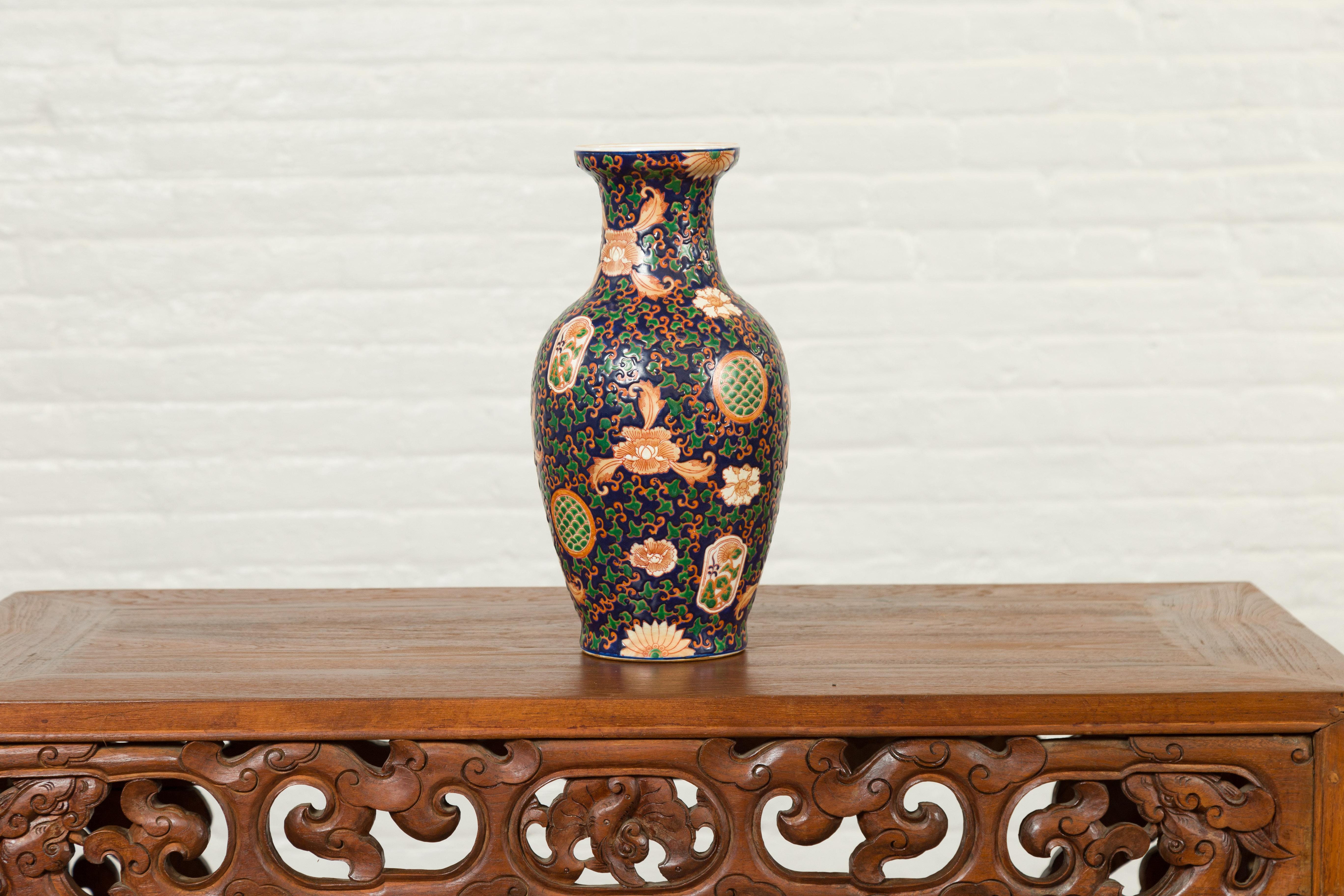 A Chinese contemporary hand painted vase with cobalt blue ground, green and orange floral decor. Charming us with its abundant motifs, this Chinese hand painted vase features a cobalt blue ground accented with delicate orange petite scrolls