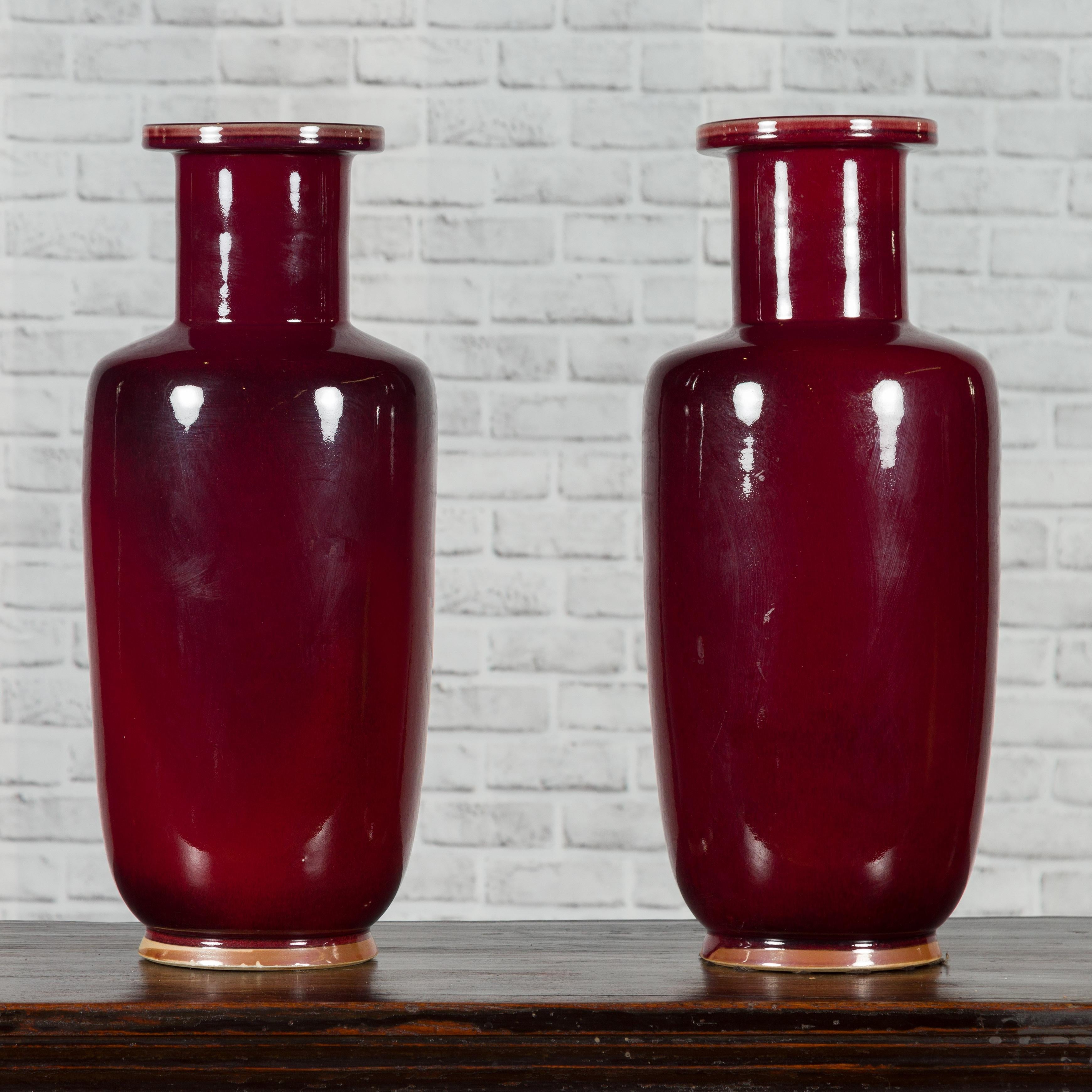 A Chinese contemporary oxblood altar vase with dark patina and tall neck. We currently have two available, priced and sold individually $590 each. Created in China during the 21st century, each of these altar vases attracts our attention with its